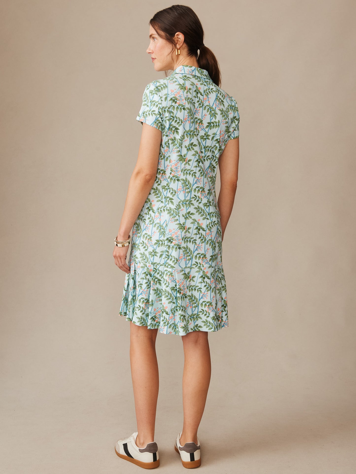 Woman seen from behind wearing a Dorte Dress in Neo Blooming Vines by J.McLaughlin, featuring a light blue base with green and pink floral pattern, embodying effortlessly stylish, enduring designs and innovative fabrics. A destination for defining style. Life, Well-Lived.
