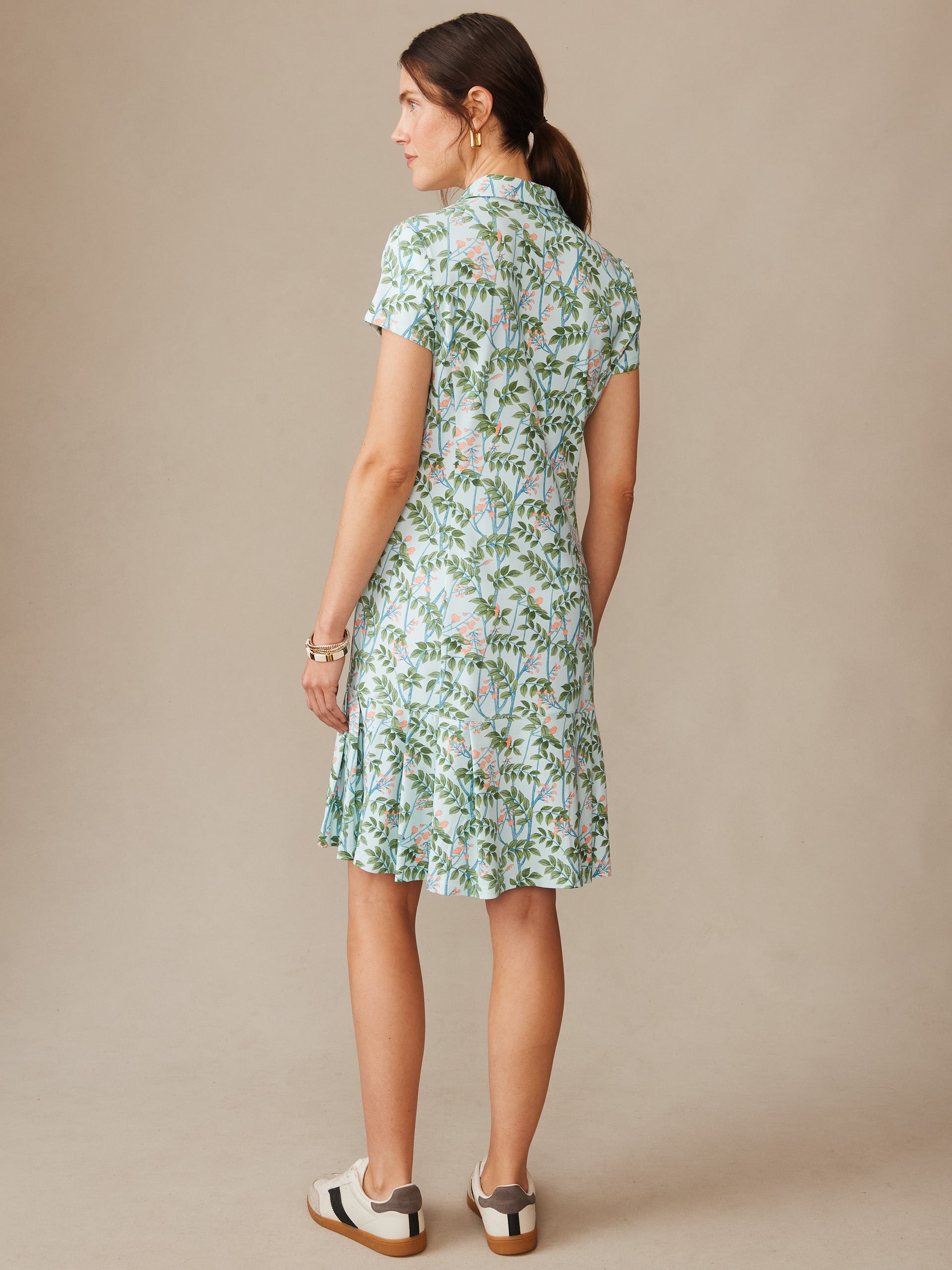Woman seen from behind wearing a Dorte Dress in Neo Blooming Vines by J.McLaughlin, featuring a light blue base with green and pink floral pattern, embodying effortlessly stylish, enduring designs and innovative fabrics. A destination for defining style. Life, Well-Lived.