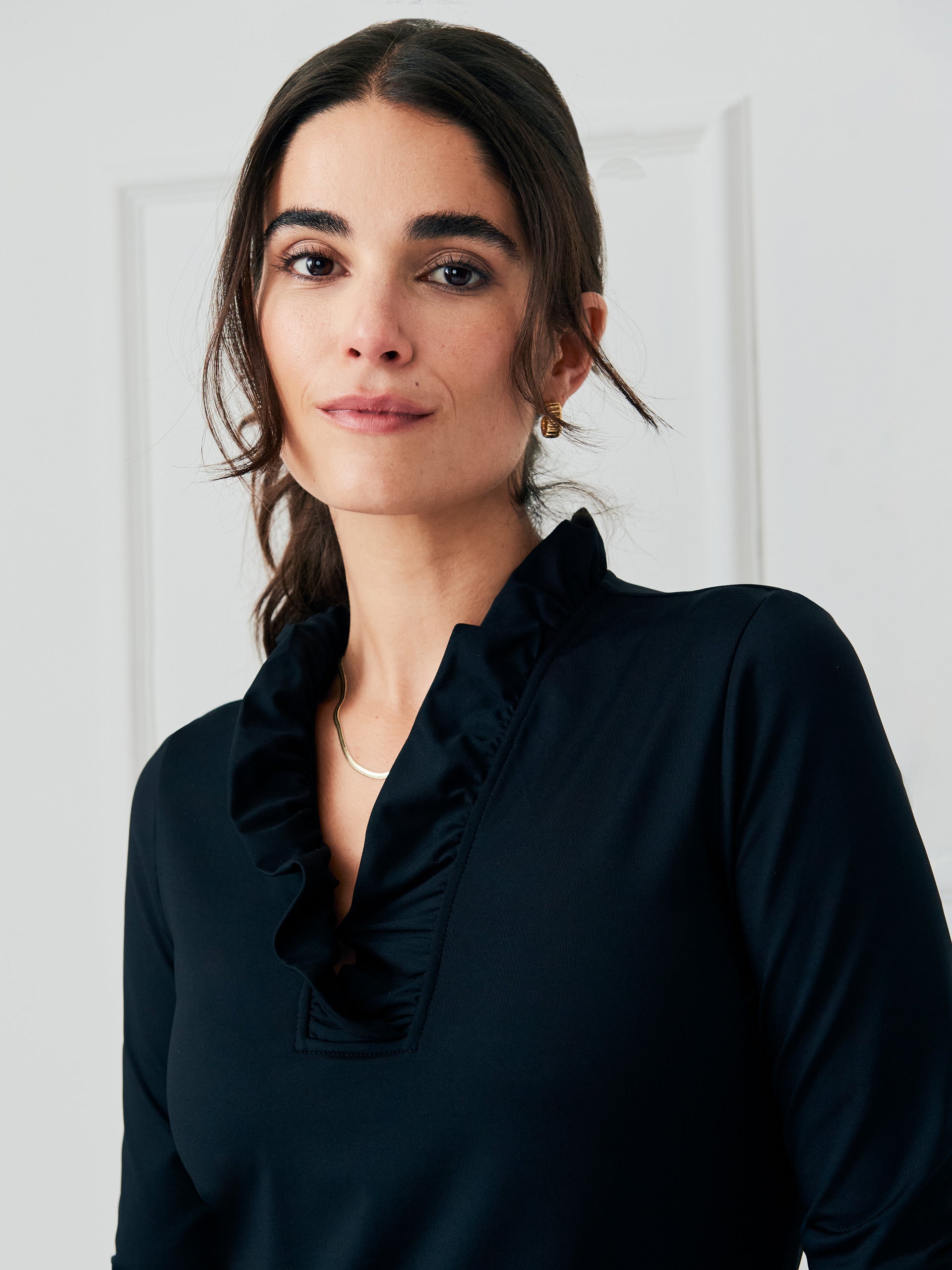 Model wearing J.McLaughlin Durham ruffle top in black made with Catalina cloth.