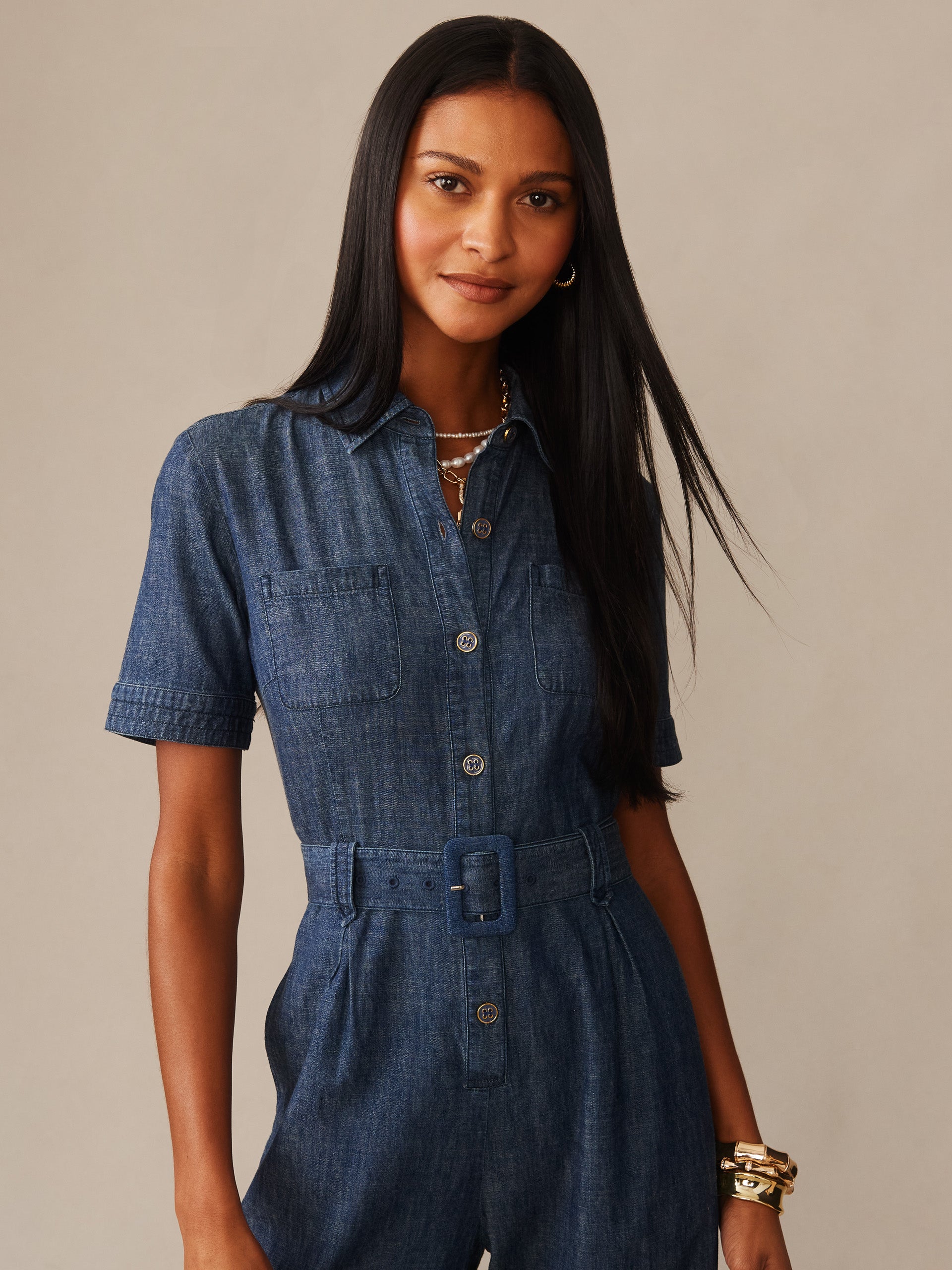 Woman wearing the Elena Jumpsuit by J.McLaughlin, featuring a classic denim fabric with short sleeves, button front, and belted waist, showcasing effortlessly stylish, enduring designs.