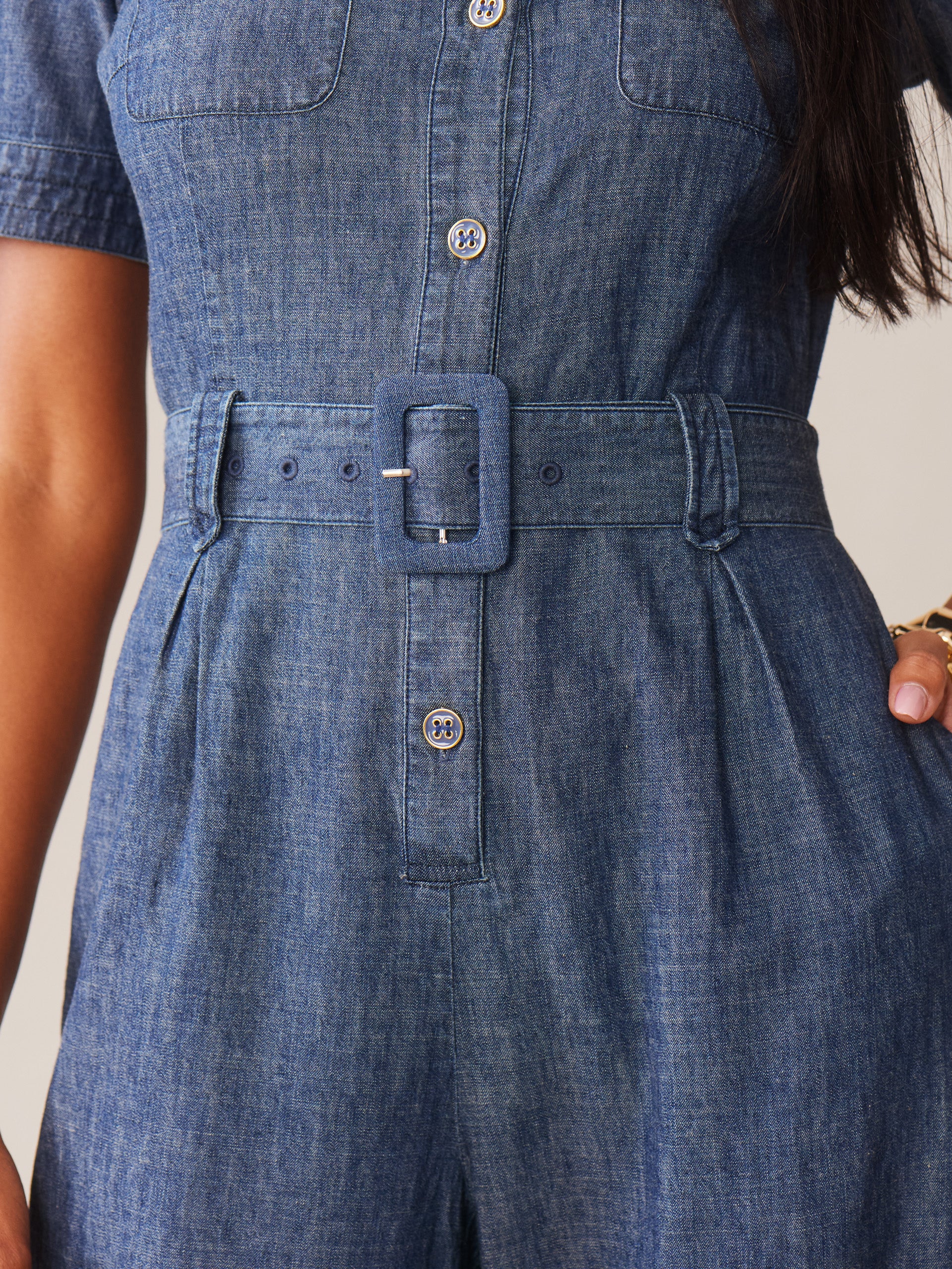 Close-up of a denim Elena Jumpsuit by J.McLaughlin featuring a matching belt with a rectangular buckle, showcasing effortlessly stylish design and enduring craftsmanship.