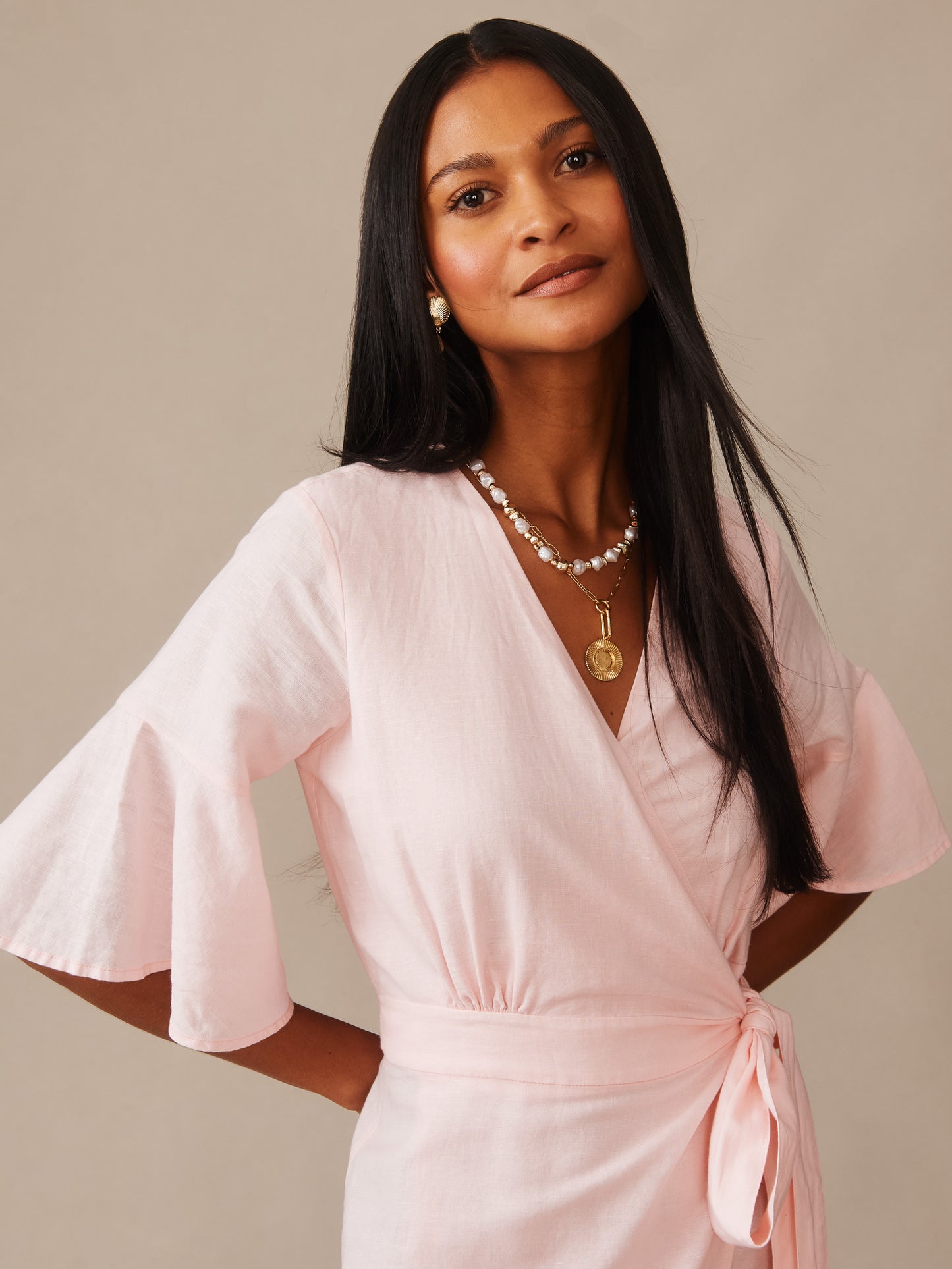 Woman wearing a soft blush pink Emily Linen Blend Wrap Dress by J.McLaughlin, showcasing effortlessly stylish design with enduring appeal in a timeless, classic silhouette.