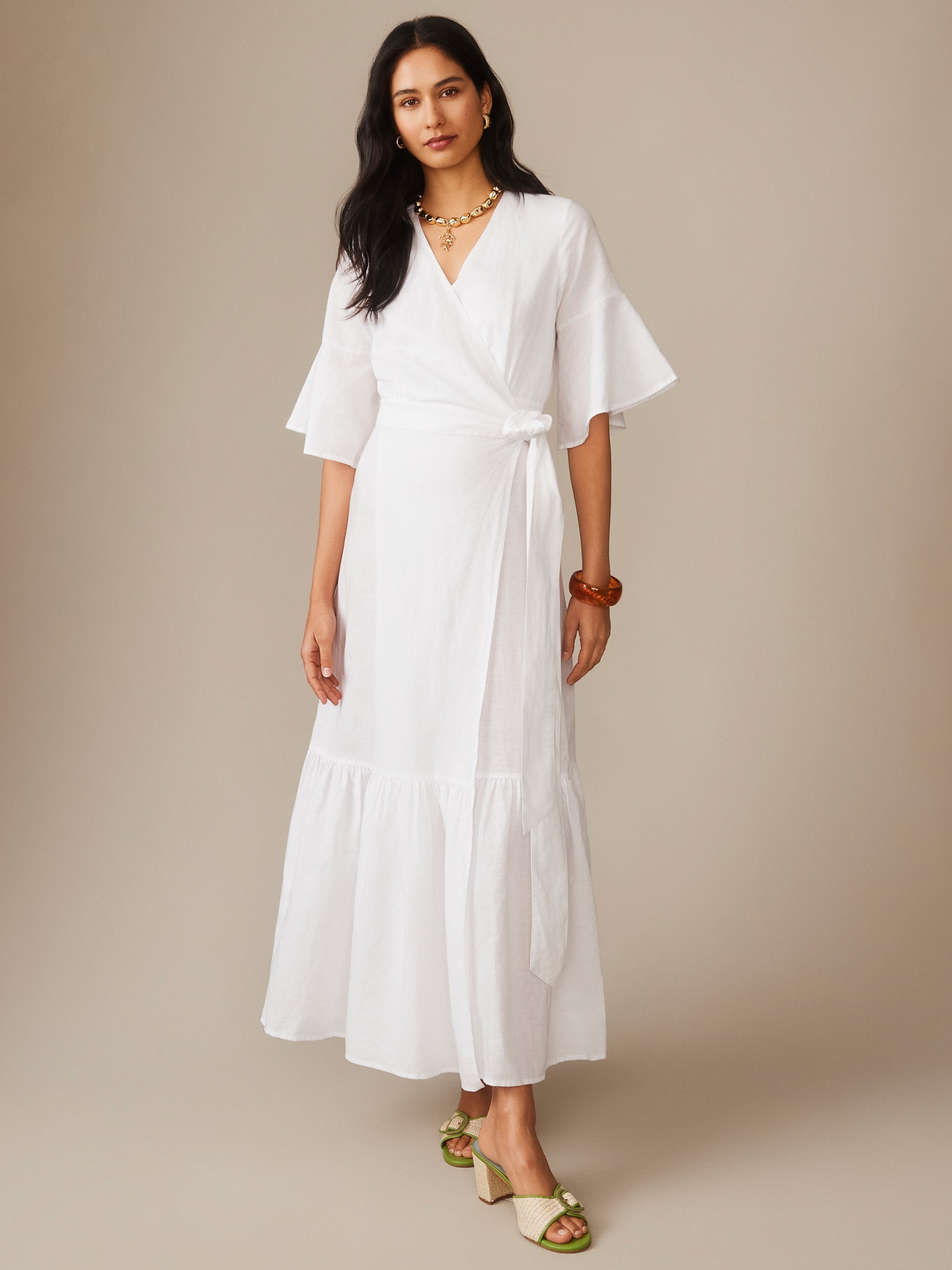 Woman wearing a white Emily Linen Blend Wrap Dress by J.McLaughlin, showcasing an effortlessly stylish, enduring design with a flattering wrap silhouette and flared sleeves, embodying a legacy of timeless fashion. A destination for defining style. Life, Well-Lived.