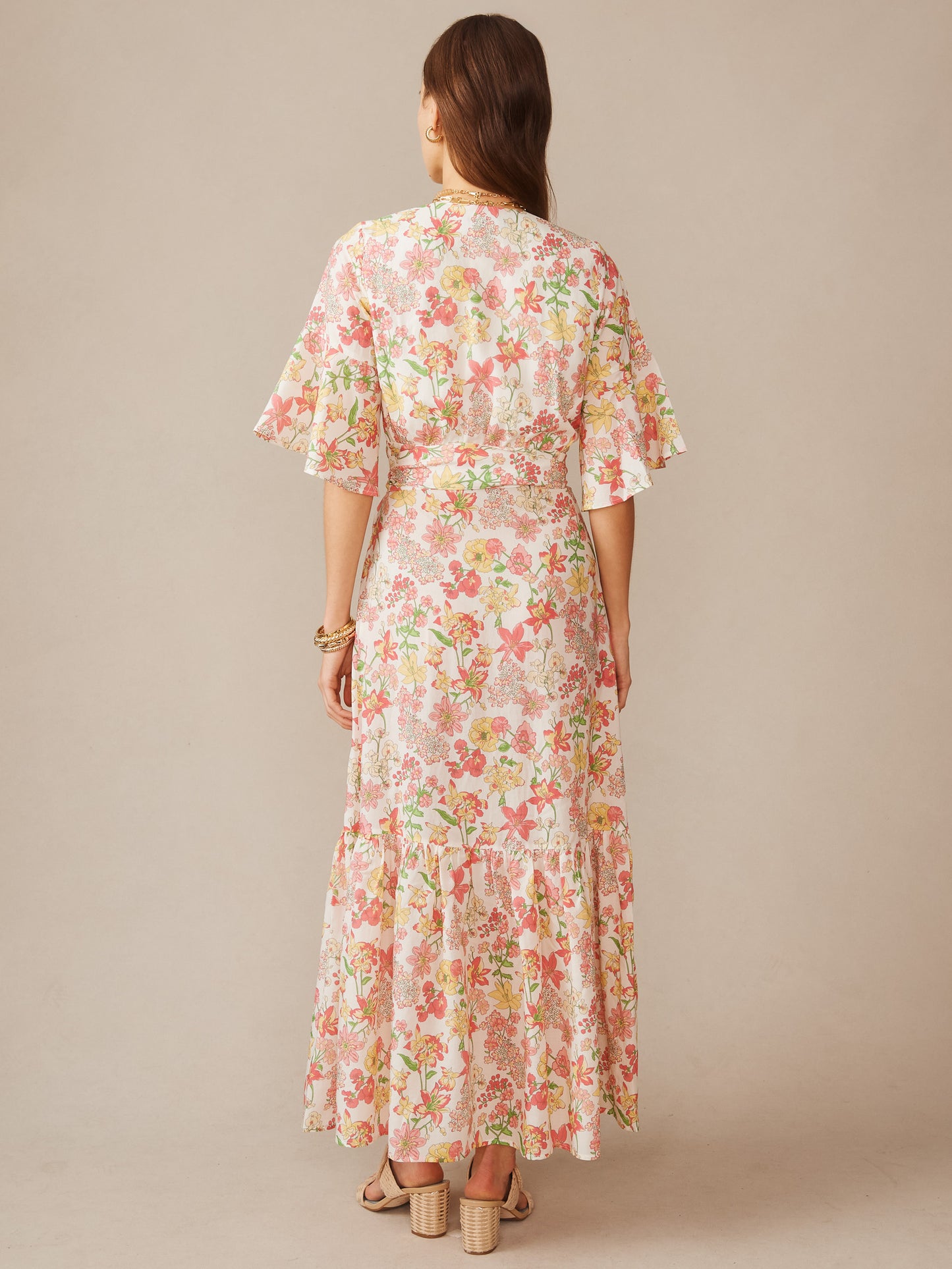 Woman wearing a flowing Emily Wrap Dress in Floral Villa by J.McLaughlin, showcasing a pastel floral pattern with ruffled sleeves and a tiered skirt in soft, timeless style.