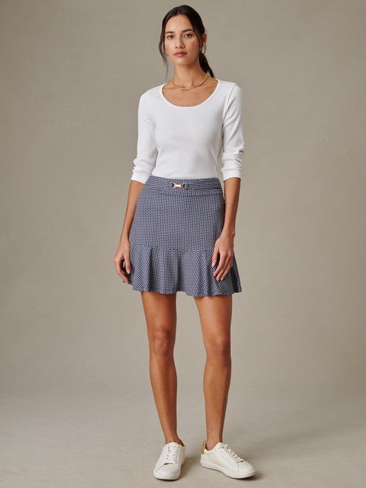 Woman wearing a white long-sleeve top paired with the Estelle Skort in Vine by J.McLaughlin, showcasing an effortlessly stylish and timeless skirt design perfect for defining style.