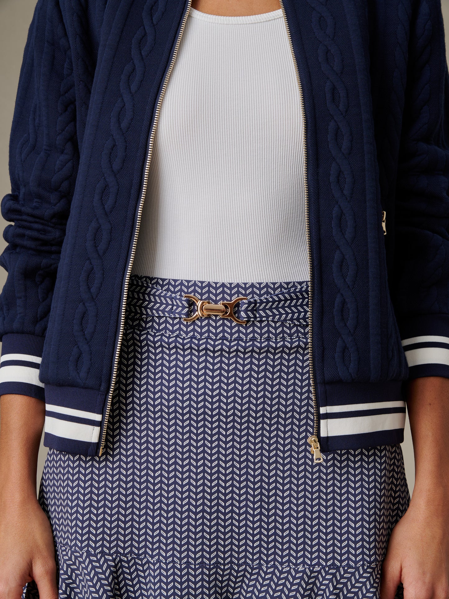 Close-up of a model wearing the Estelle Skort in Vine by J.McLaughlin styled with a white ribbed top and a navy blue quilted jacket, showcasing effortless style and enduring design.