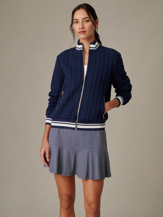 Woman wearing a navy Willa Jacket in Cable Jacquard by J.McLaughlin, styled with a patterned skirt, showcasing effortlessly stylish, enduring designs for a life well-lived.