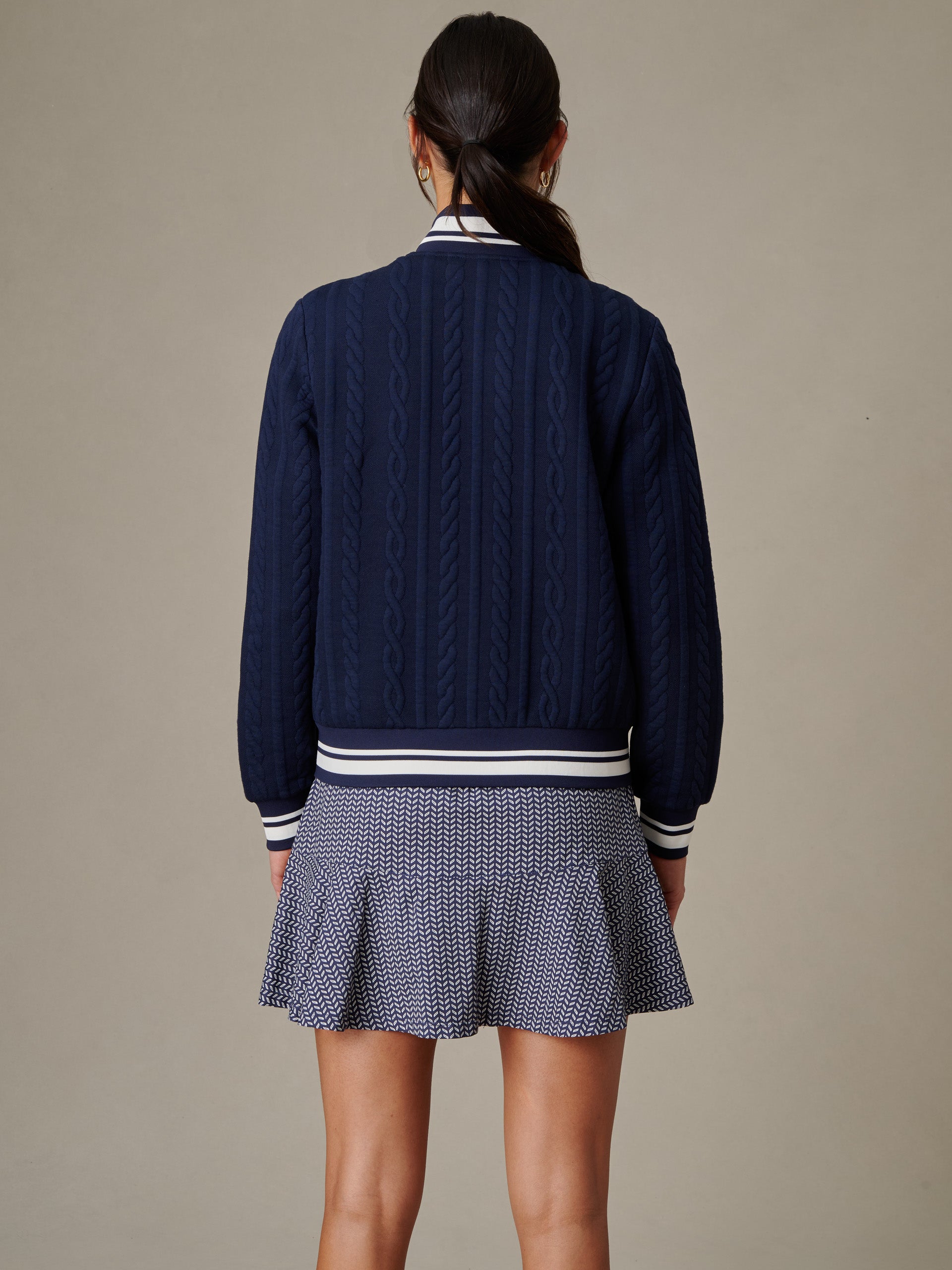 Woman wearing the Willa Jacket in Cable Jacquard by J.McLaughlin, showcasing innovative fabric and timeless design in a classic navy cable knit style.