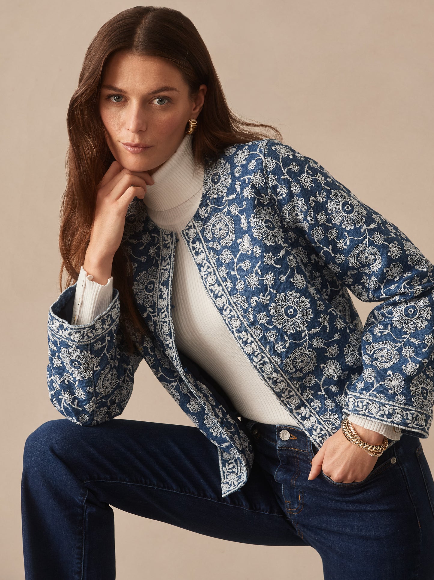 Woman wearing the Isabel Jacket in Floral Daydream Embroidery by J.McLaughlin over a white turtleneck and dark jeans, showcasing effortlessly stylish, enduring designs and timeless craftsmanship.