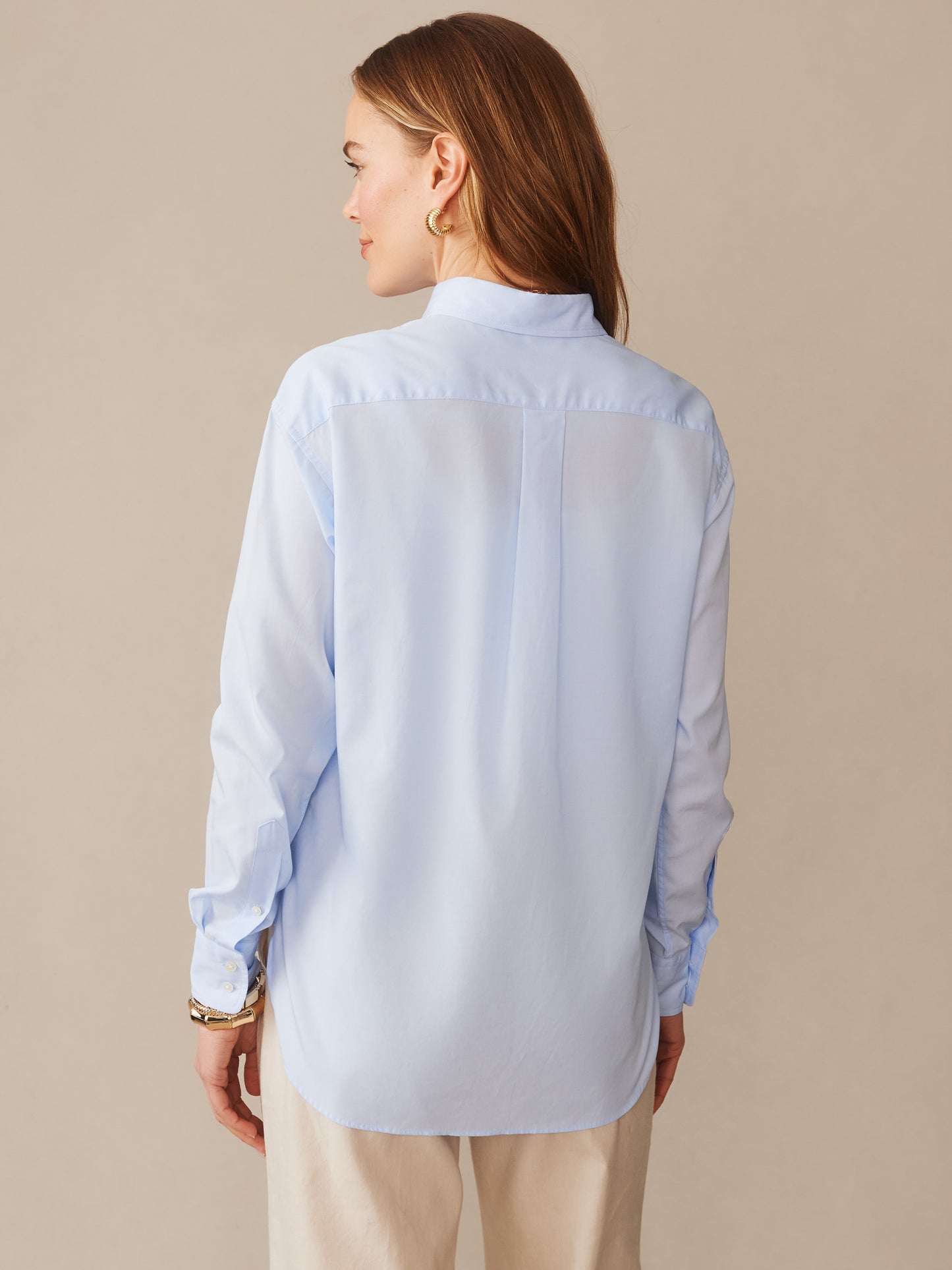 A woman wearing a light blue Finn Shirt by J.McLaughlin, showcasing effortlessly stylish, enduring designs crafted with innovative fabrics, embodying a legacy of timeless fashion.