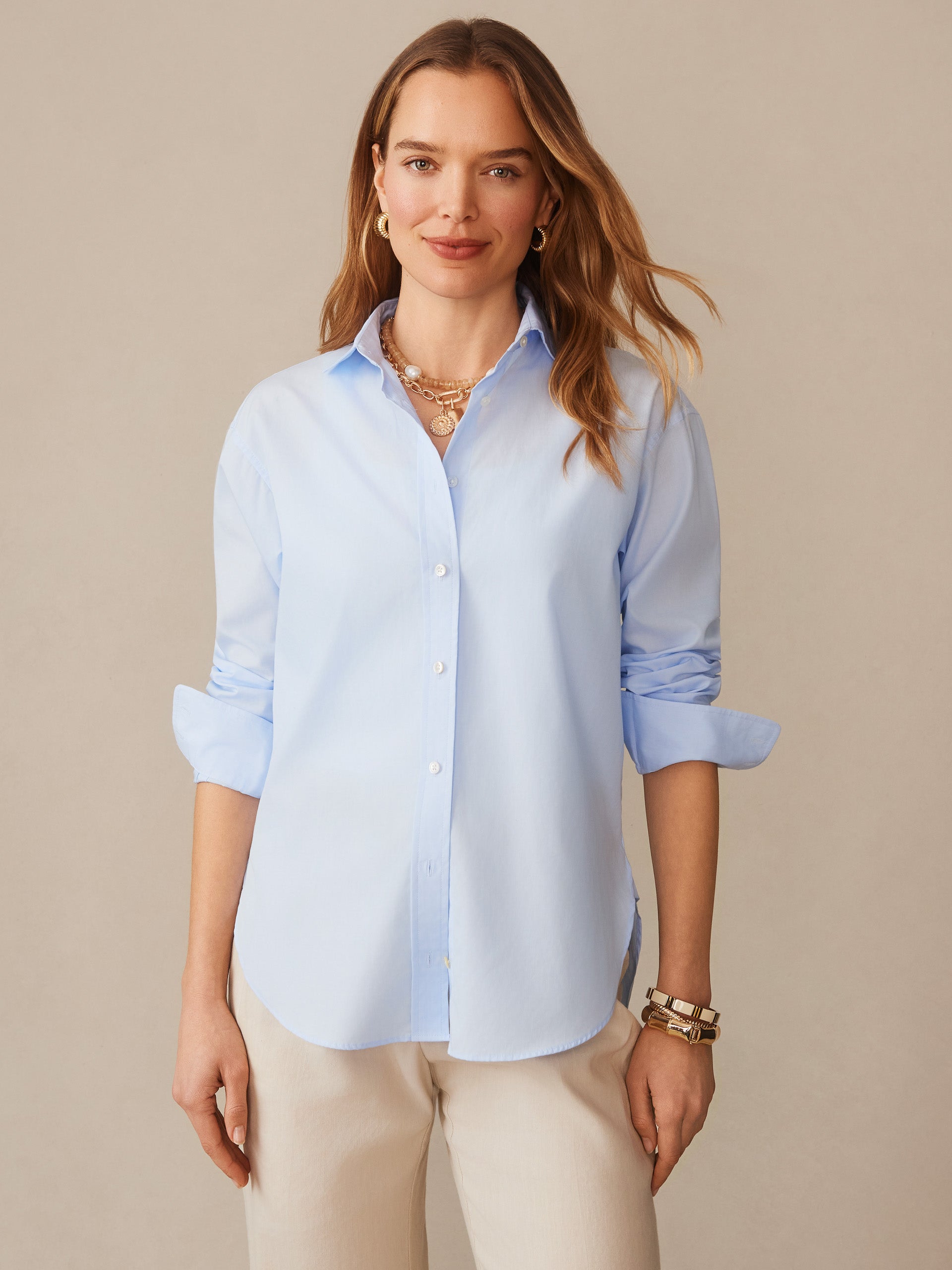 A woman wearing a light blue Finn Shirt by J.McLaughlin paired with beige pants, showcasing effortlessly stylish, enduring designs and innovative fabrics for a legacy of timeless fashion.