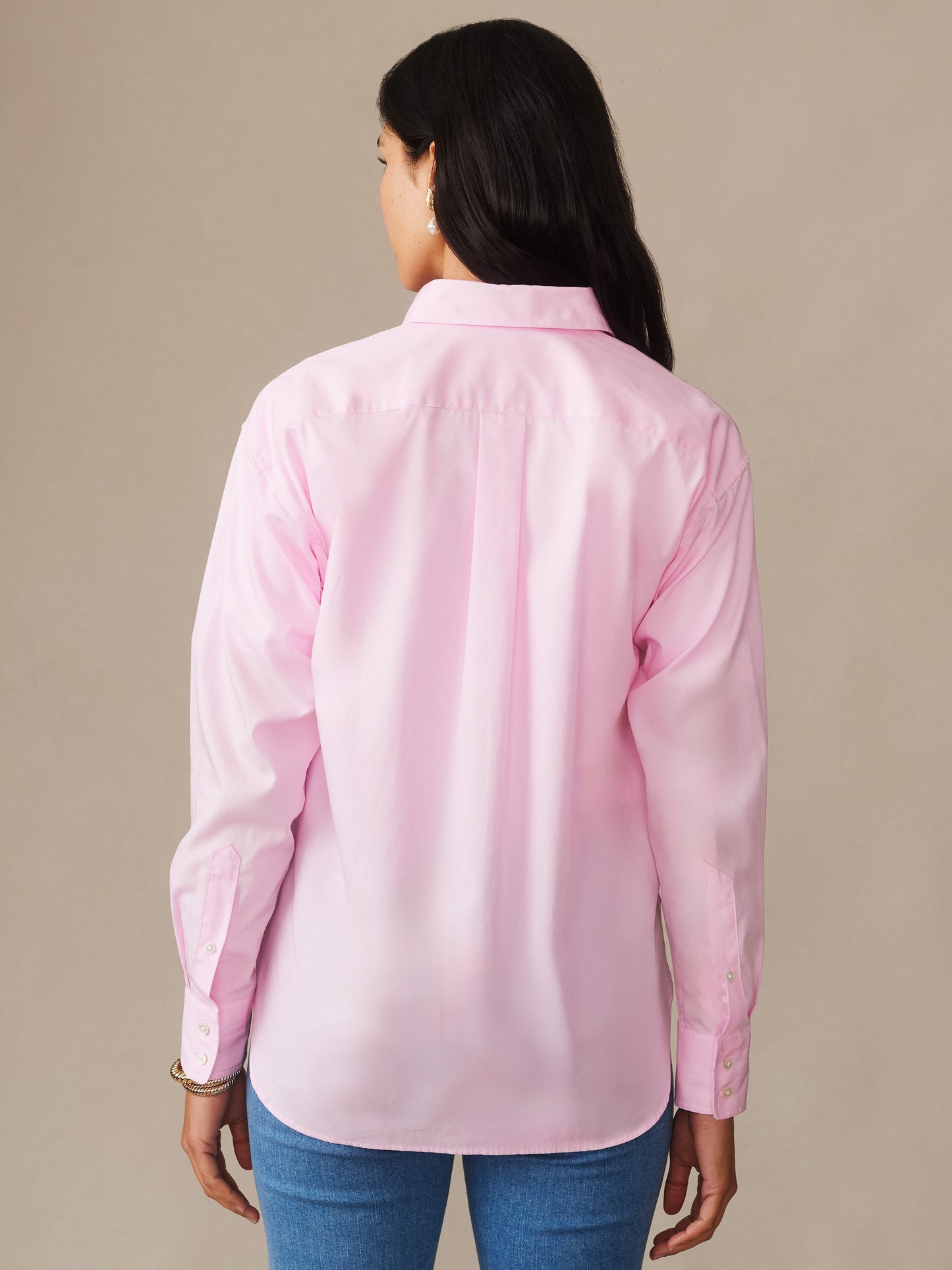 A woman wearing a light pink Finn Shirt by J.McLaughlin showcases its clean, classic design from the back, highlighting enduring style with innovative fabrics and impeccable craftsmanship.
