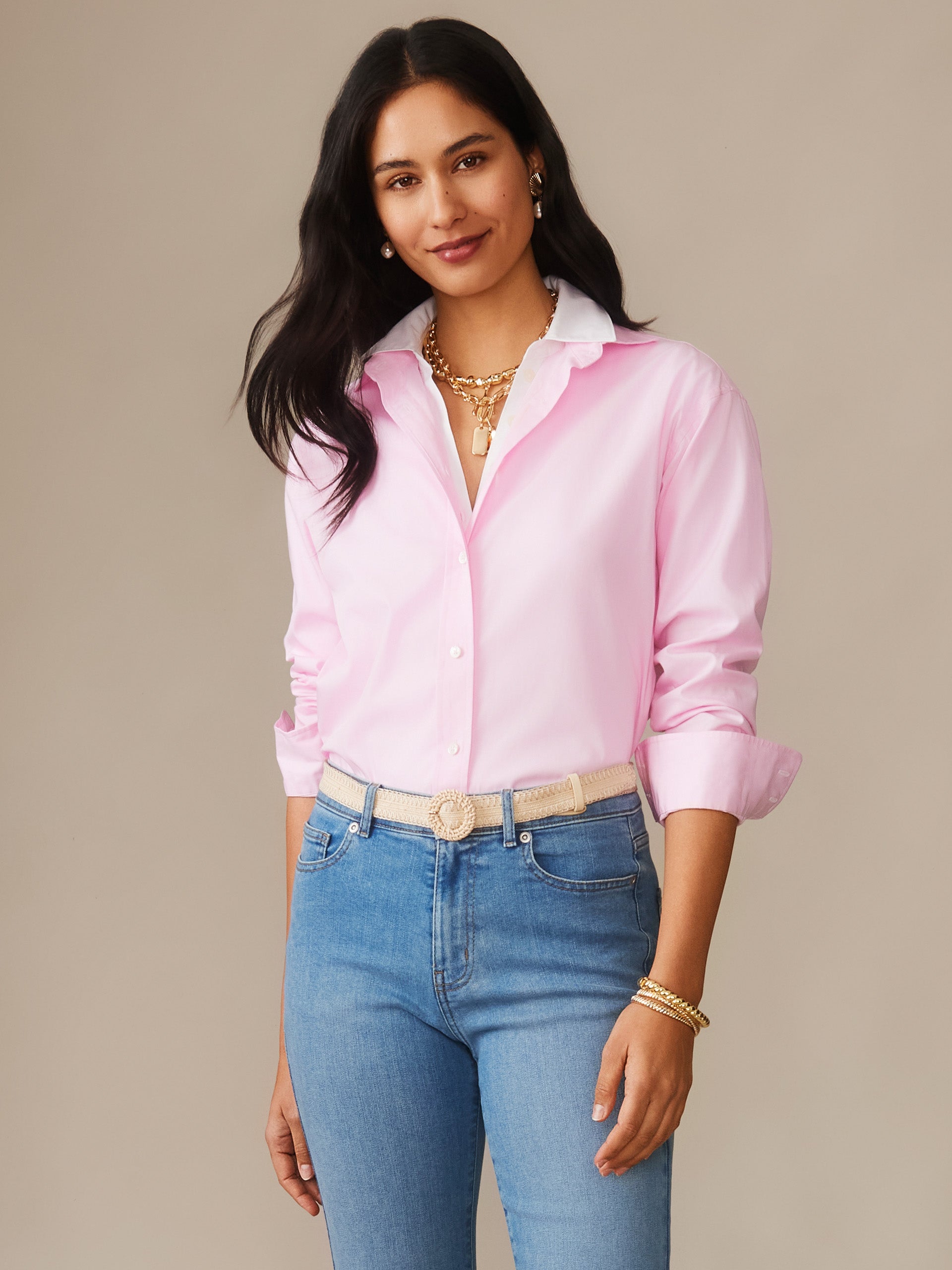 Woman wearing a pink Finn Shirt by J.McLaughlin paired with blue jeans and gold jewelry, showcasing effortlessly stylish, enduring designs with innovative fabrics from a destination for defining style. Life, Well-Lived.