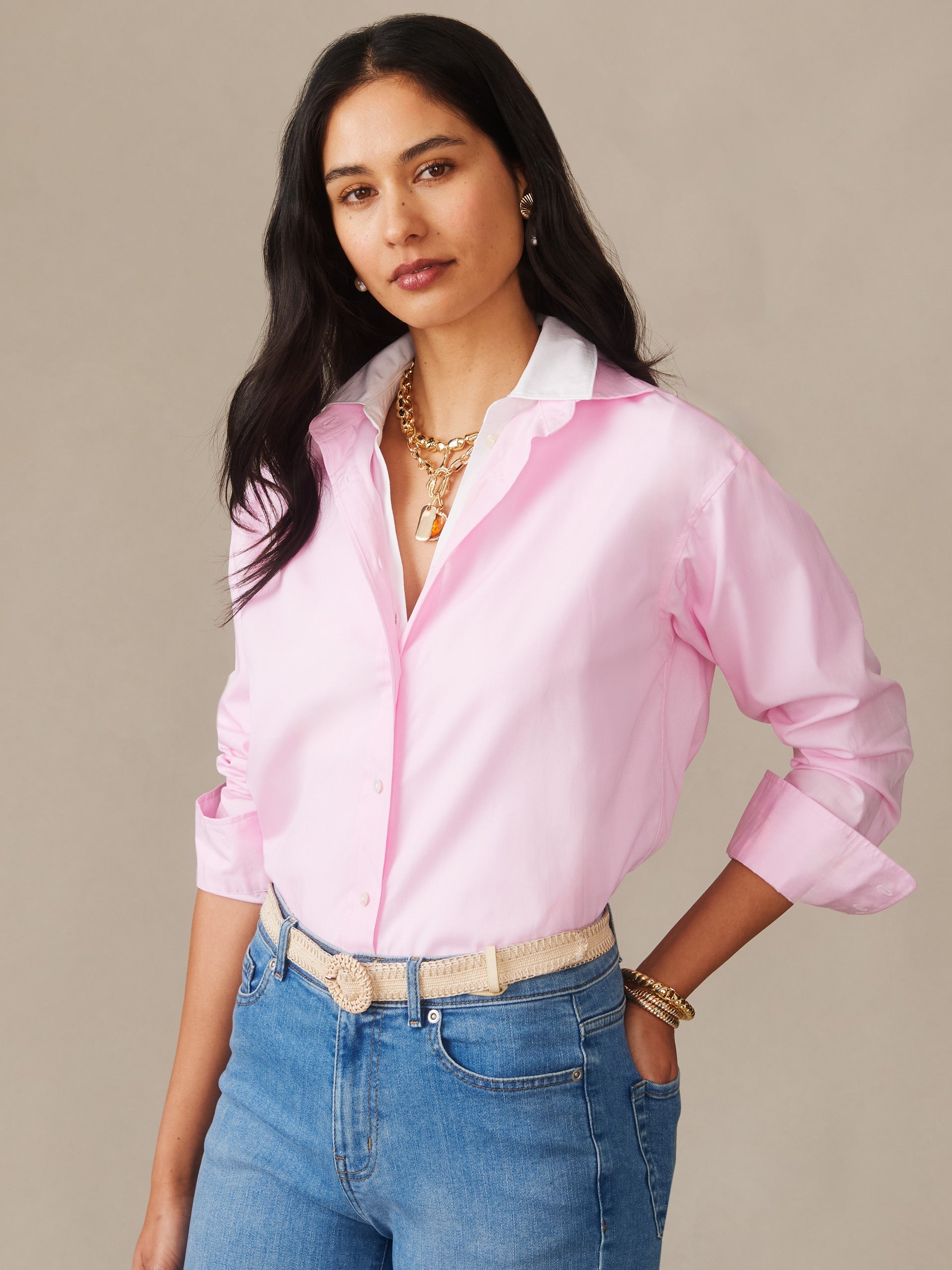 Woman wearing a pink Finn Shirt by J.McLaughlin paired with blue jeans and layered gold jewelry, showcasing effortlessly stylish, enduring designs and innovative fabrics at a destination for defining style. Life, Well-Lived.