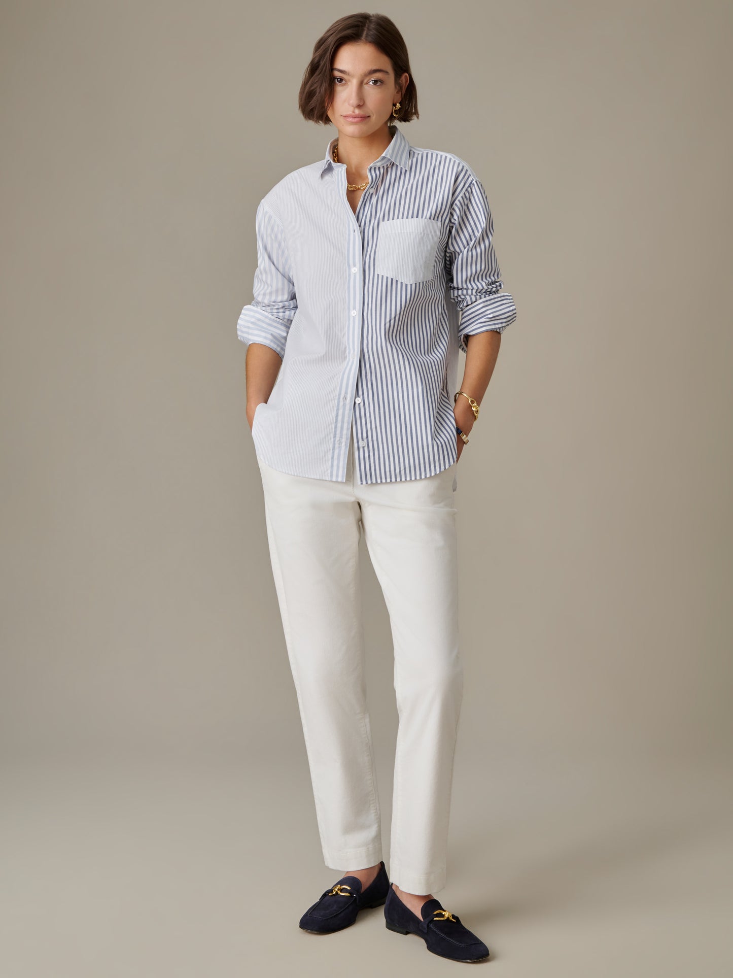 Woman wearing a Finn Shirt in Stripe by J.McLaughlin paired with white pants and black loafers, showcasing effortlessly stylish design and enduring classic appeal.