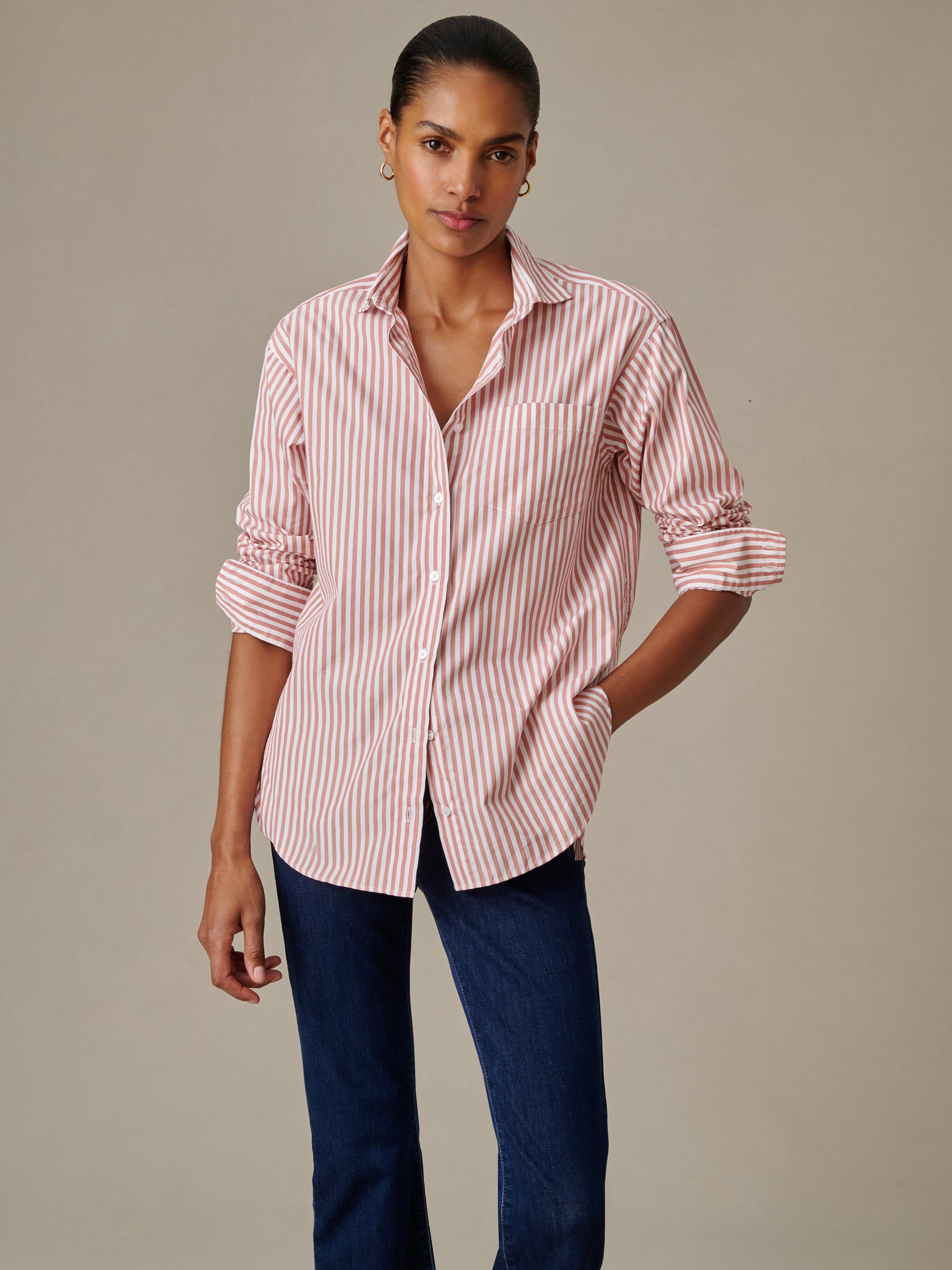 Woman wearing a Finn Shirt in Stripe by J.McLaughlin featuring a relaxed fit with rolled-up sleeves, paired with dark jeans, showcasing timeless style and enduring design.