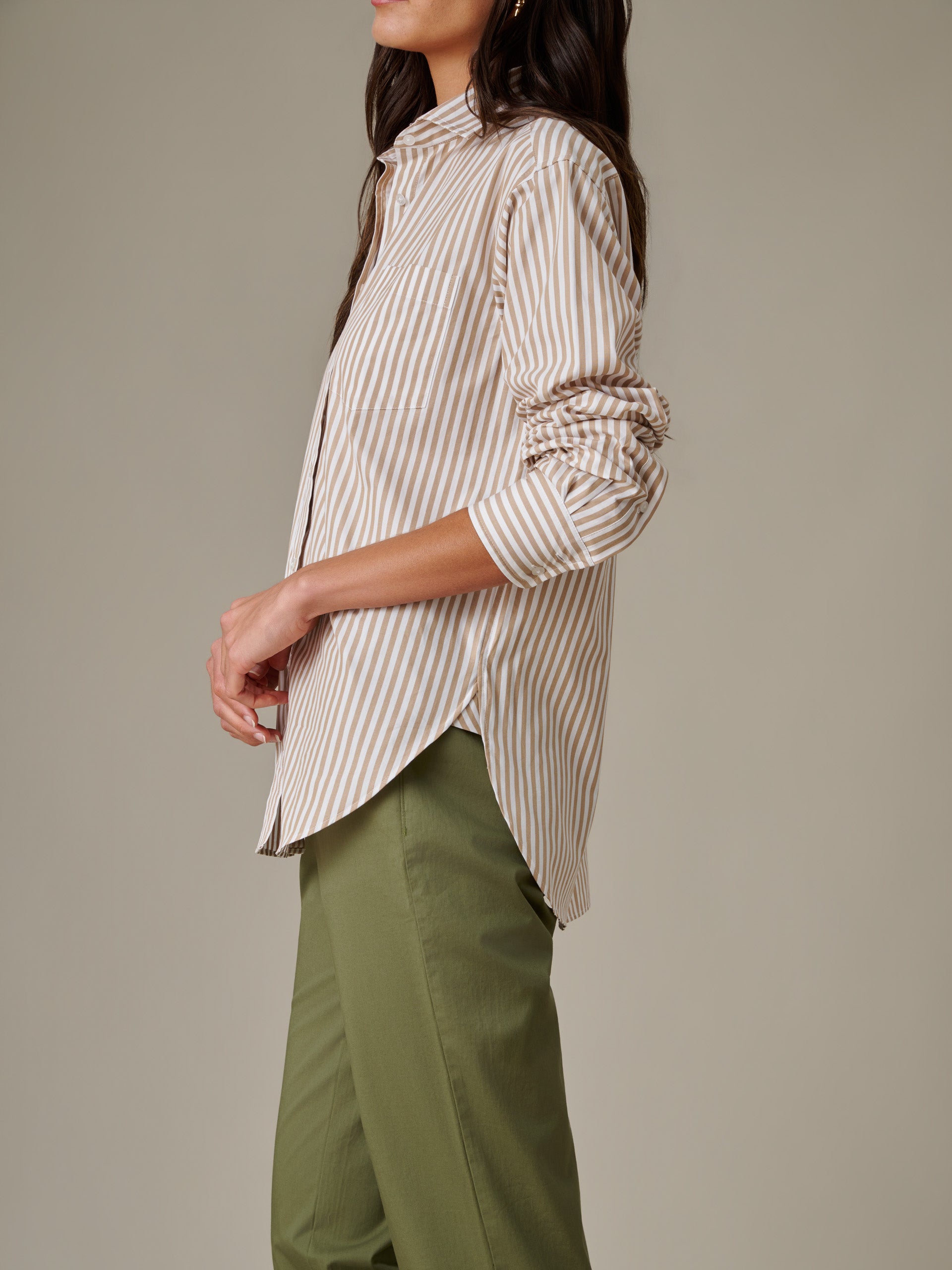 Side view of a woman wearing the Finn Shirt in Stripe by J.McLaughlin paired with olive green pants, showcasing timeless style and impeccable craftsmanship.