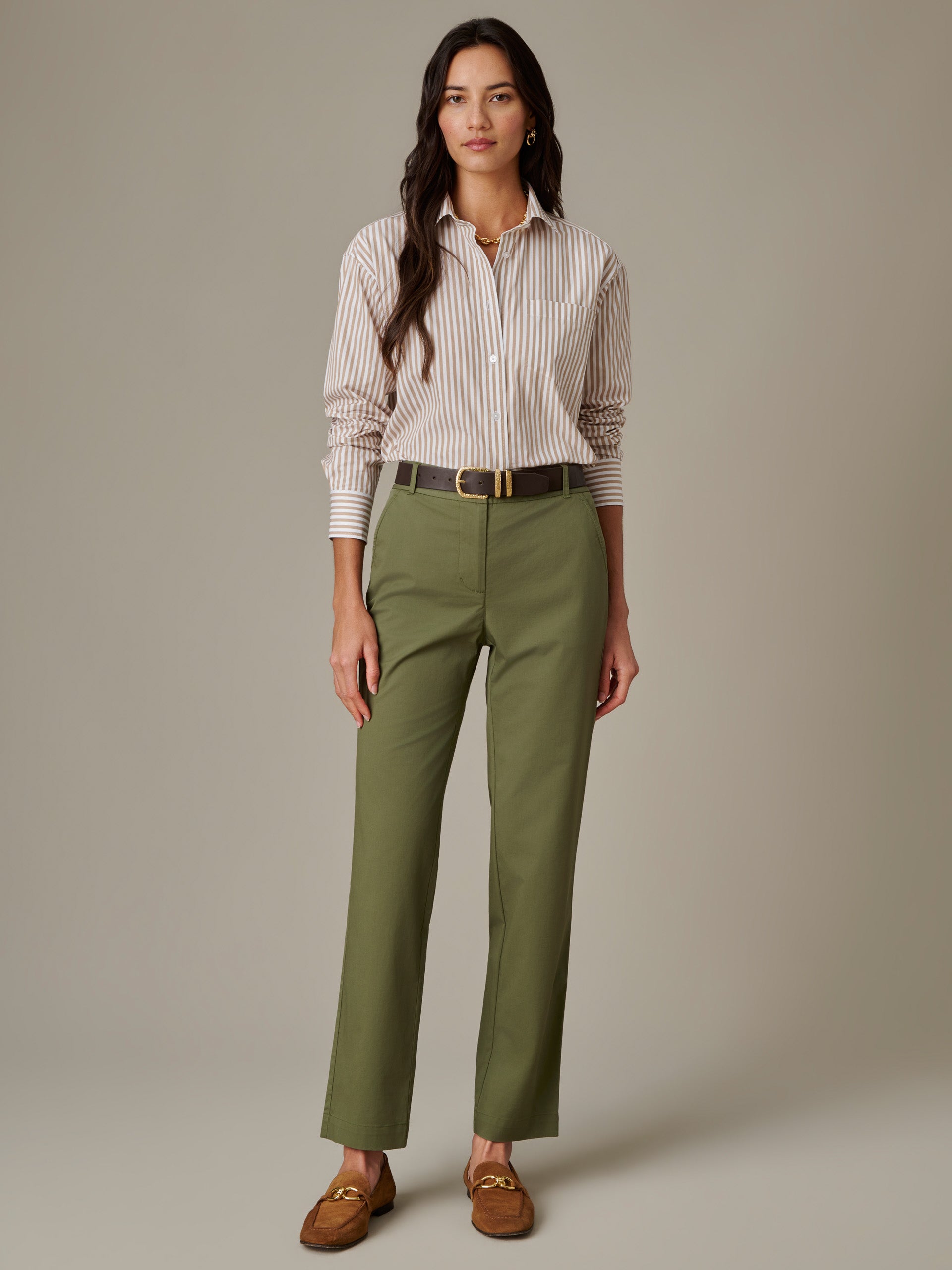 Woman wearing a Finn Shirt in Stripe by J.McLaughlin, styled with olive green pants, a black belt, and brown loafers, showcasing timeless, effortlessly stylish design.