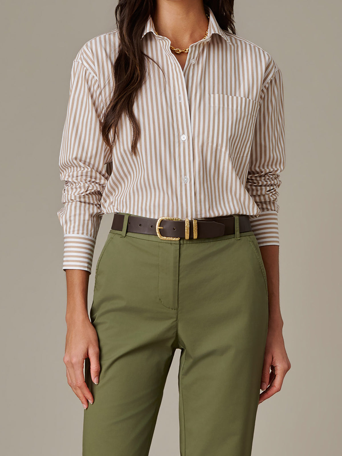 Woman wearing a Kendall Leather Belt by J.McLaughlin styled with olive pants and a beige striped blouse, showcasing an effortlessly stylish and timeless accessory.