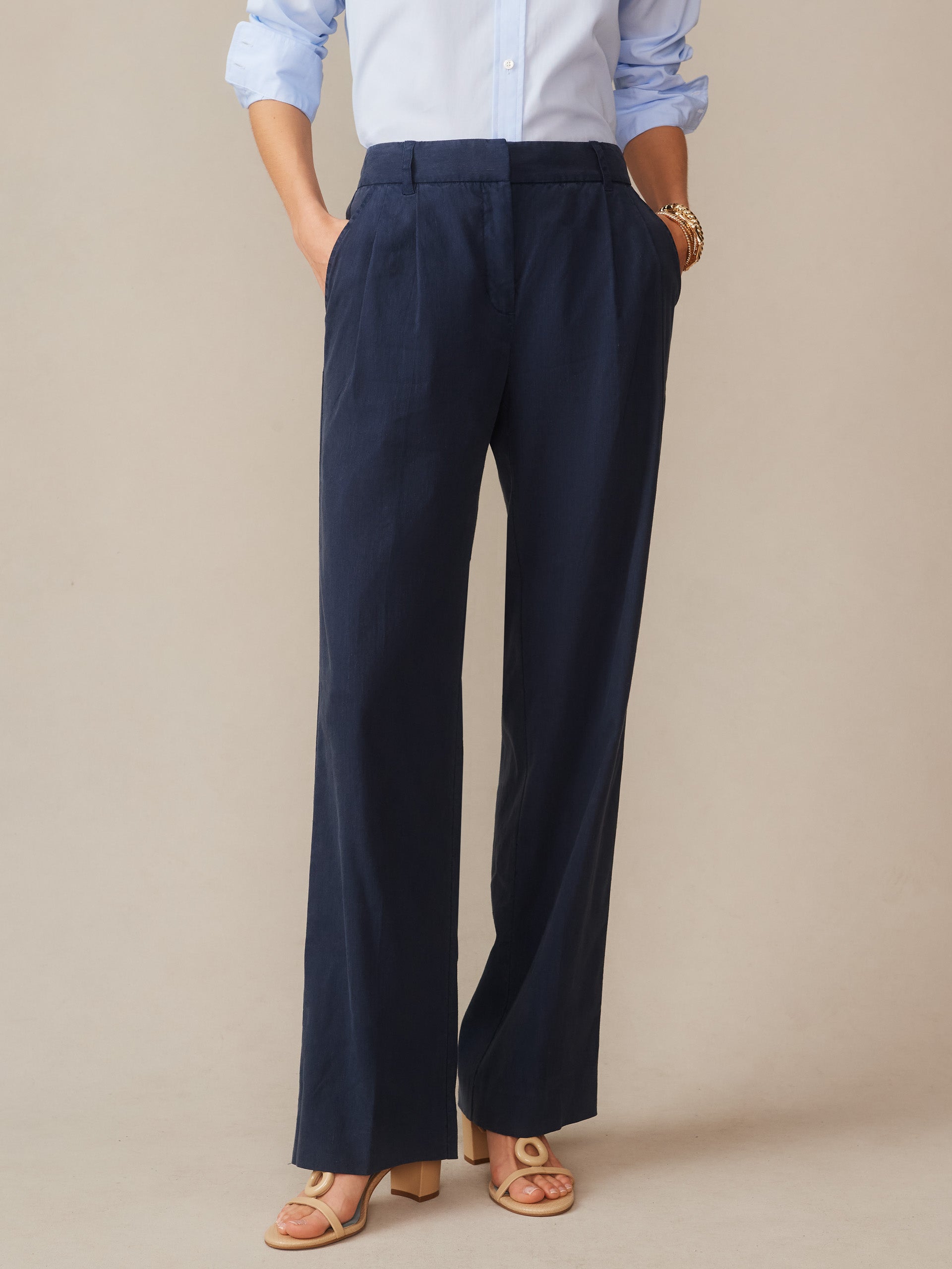 Woman wearing navy blue Fiona Linen Blend Pants paired with a light blue blouse and nude sandals, showcasing J.McLaughlin’s enduring designs and innovative fabrics in effortlessly stylish fashion.