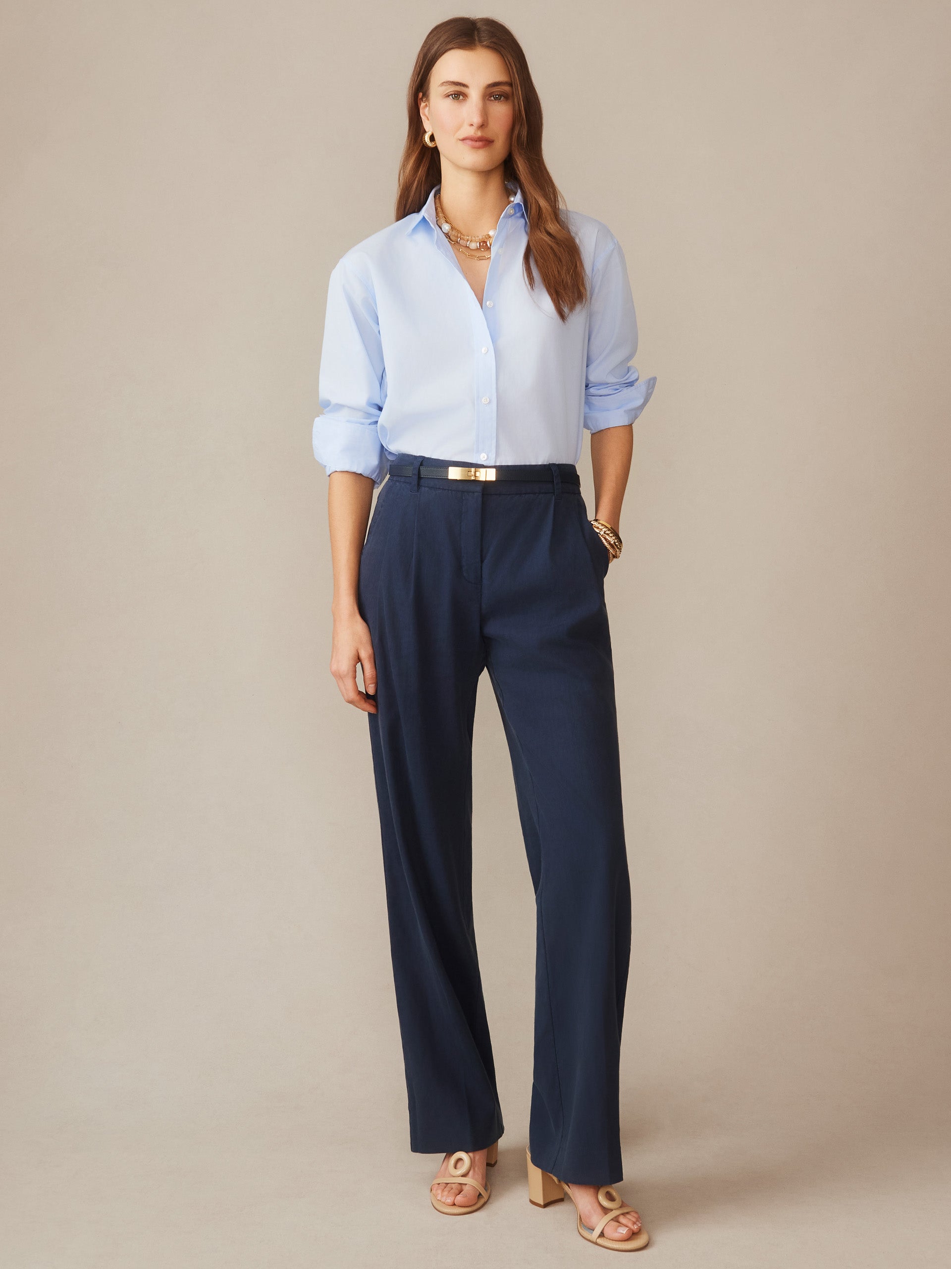 A woman wearing J.McLaughlin Fiona Linen Blend Pants in navy paired with a light blue button-down shirt, showcasing effortlessly stylish, enduring designs crafted for a life well-lived.
