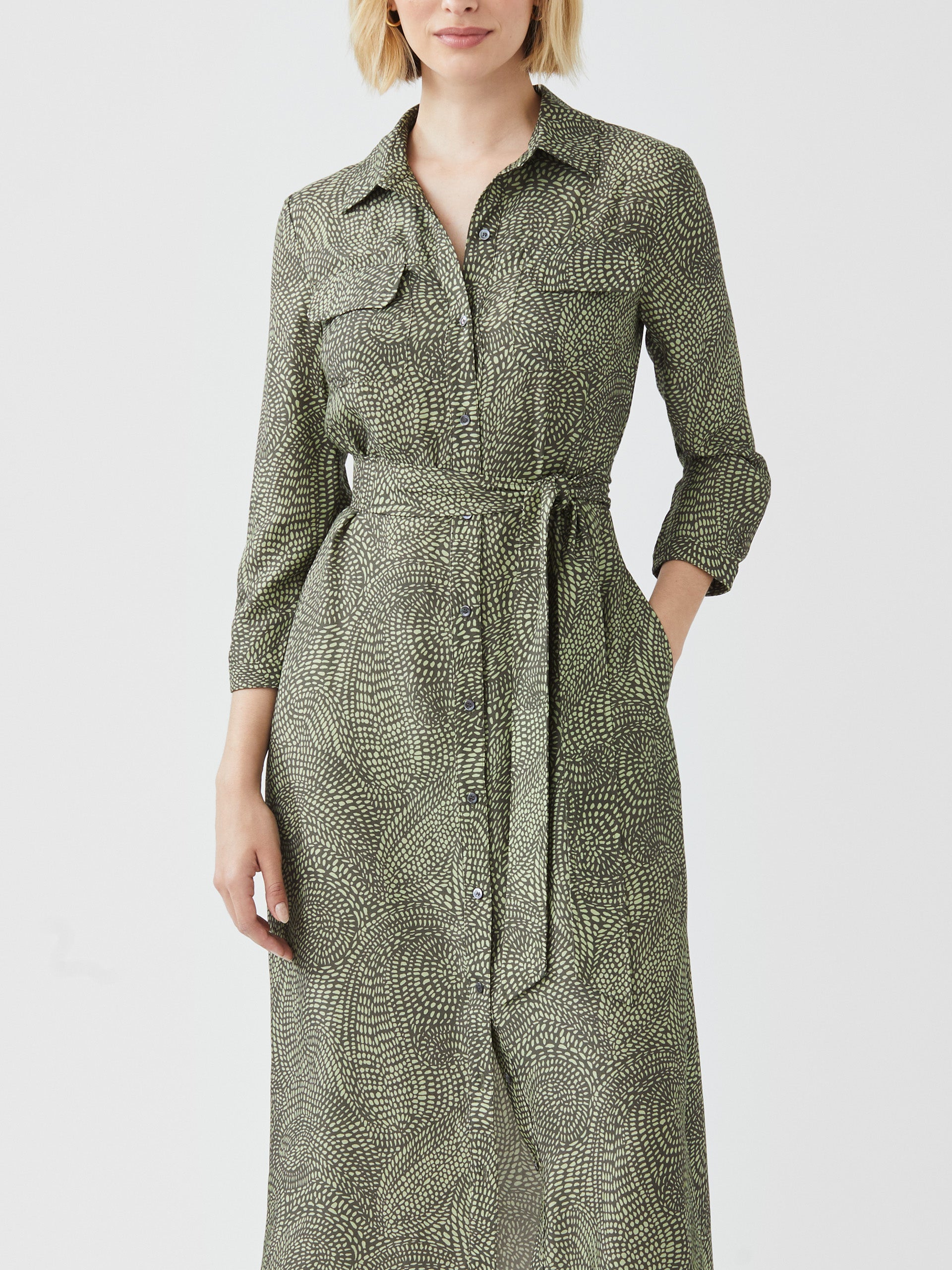 Model wearing J.McLaughlin Freda dress in olive/green made with viscose and silk.