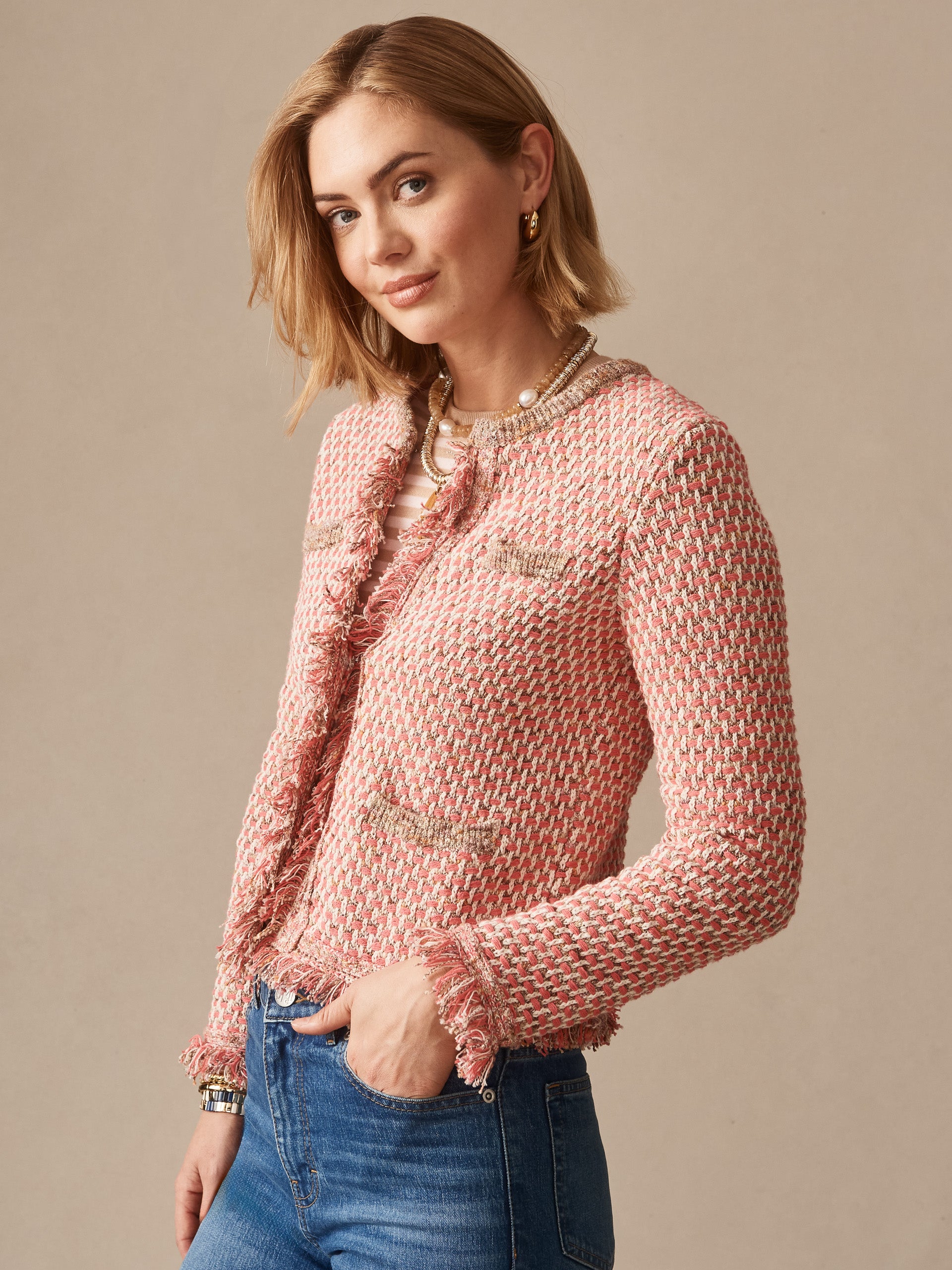 Woman wearing a pink and tan textured Marceline Cardigan by J.McLaughlin paired with jeans, showcasing effortlessly stylish, enduring designs and a legacy of timeless fashion. A destination for defining style. Life, Well-Lived.