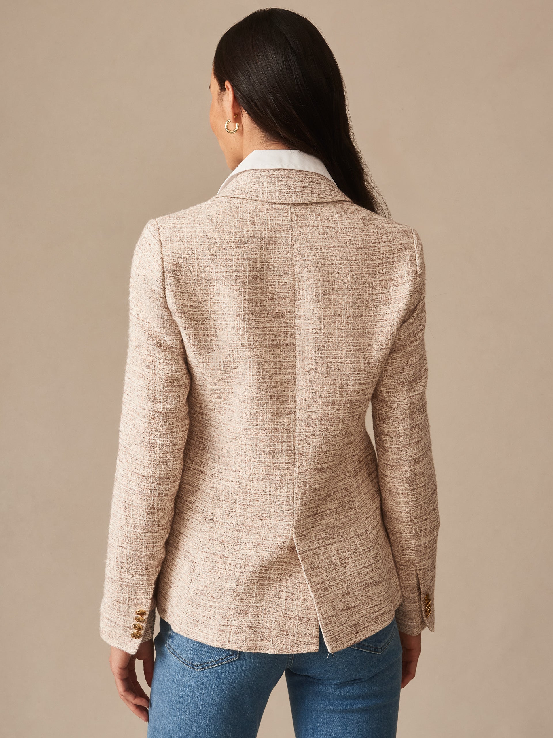 Back view of a woman wearing the Genevieve Tweed Blazer by J.McLaughlin, featuring a textured tan and white tweed fabric with a tailored fit and a center back vent.