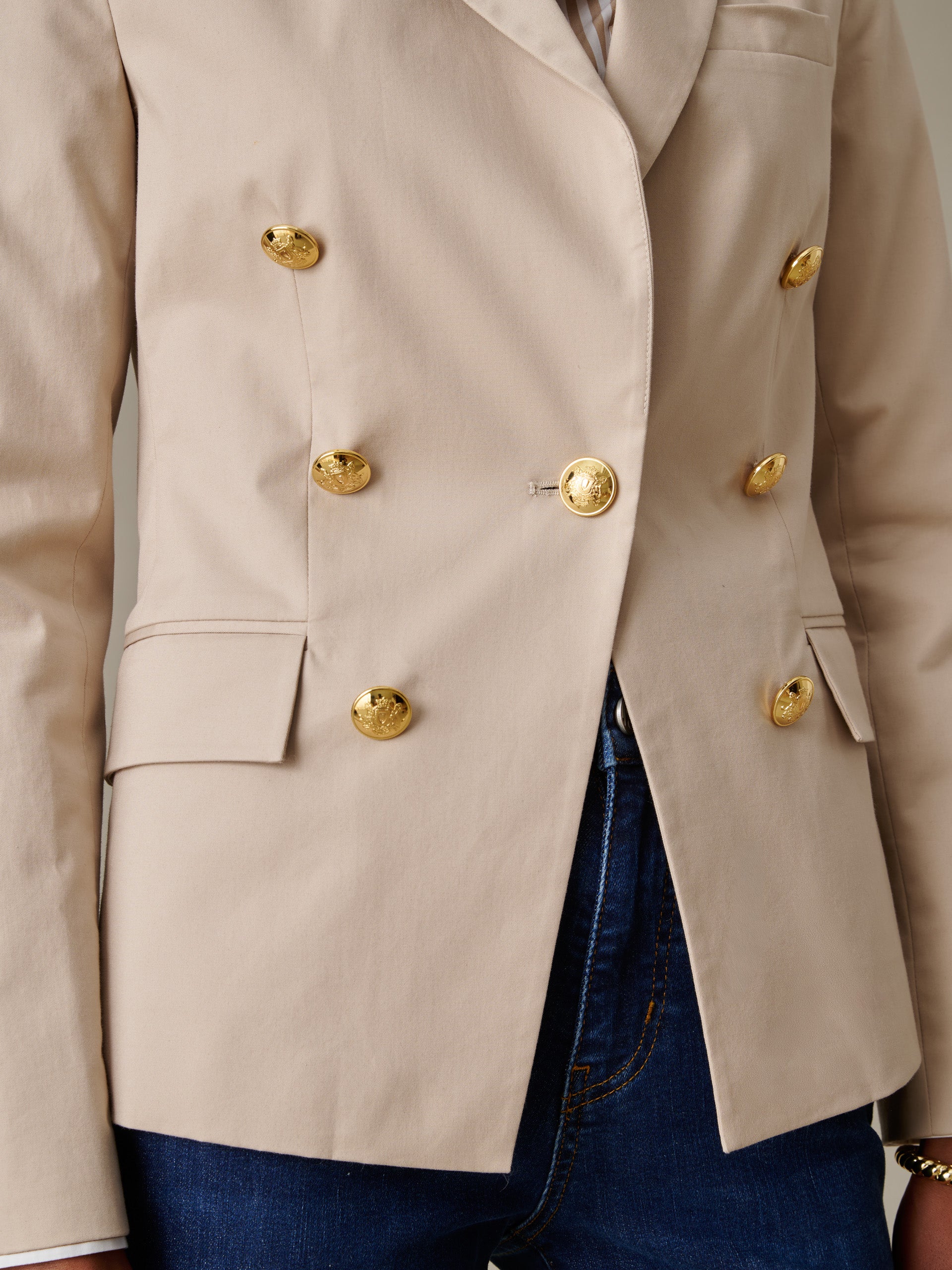 Close-up of a beige Genevieve Cotton Twill Blazer by J.McLaughlin featuring gold buttons, tailored pockets, and a timeless, effortlessly stylish design perfect for a life well-lived.