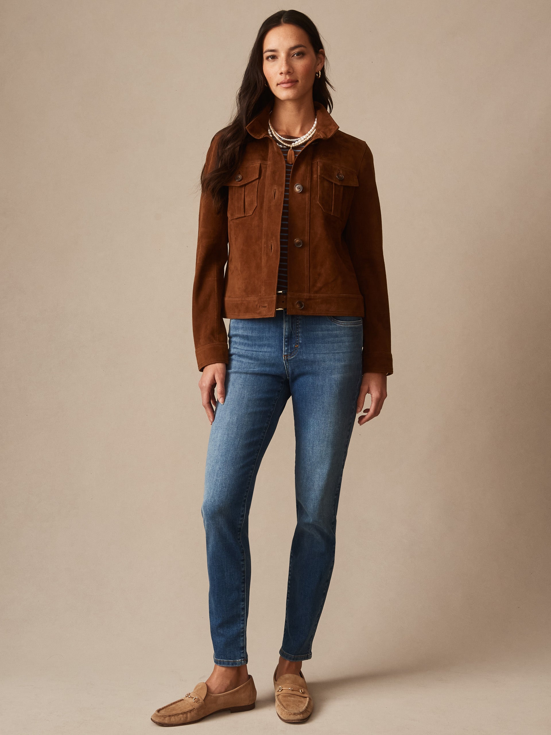 Woman wearing a brown Frances Suede Jacket by J.McLaughlin paired with blue jeans and loafers, showcasing effortlessly stylish and enduring designs for timeless fashion.