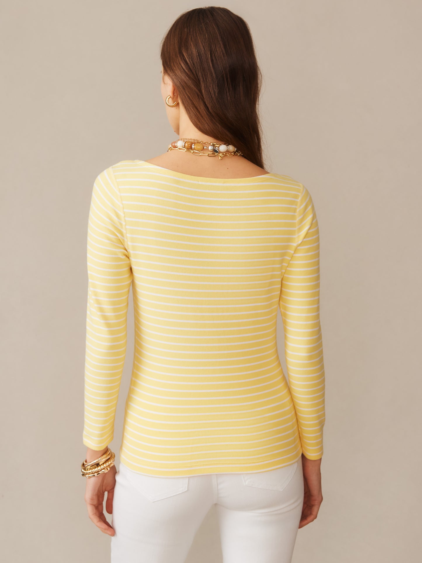 A woman wearing the Goldie Tee in Stripe by J.McLaughlin in soft yellow and white stripes, showcasing effortlessly stylish design and enduring quality, embodying a destination for defining style. Life, Well-Lived.