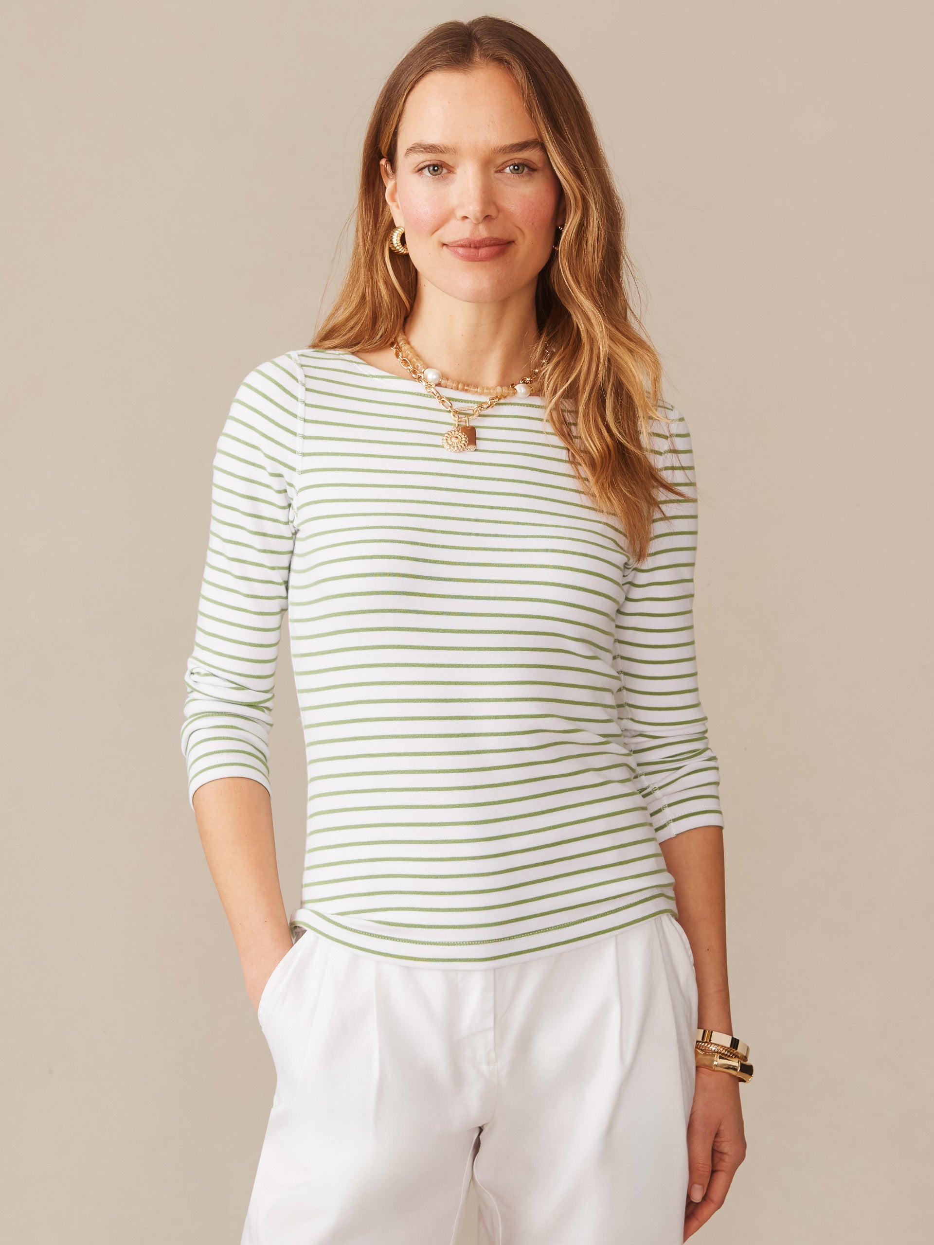 Woman wearing a J.McLaughlin Goldie Tee in Stripe with green and white stripes, accessorized with gold jewelry, embodying effortlessly stylish, enduring designs and innovative fabrics.