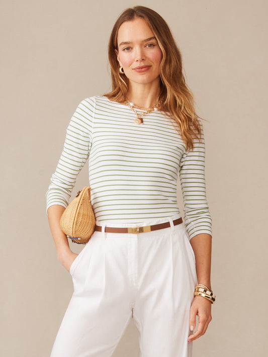 Woman wearing a Goldie Tee in Stripe by J.McLaughlin, featuring light green and white stripes, styled with white pants and gold accessories, showcasing effortlessly stylish and enduring designs.