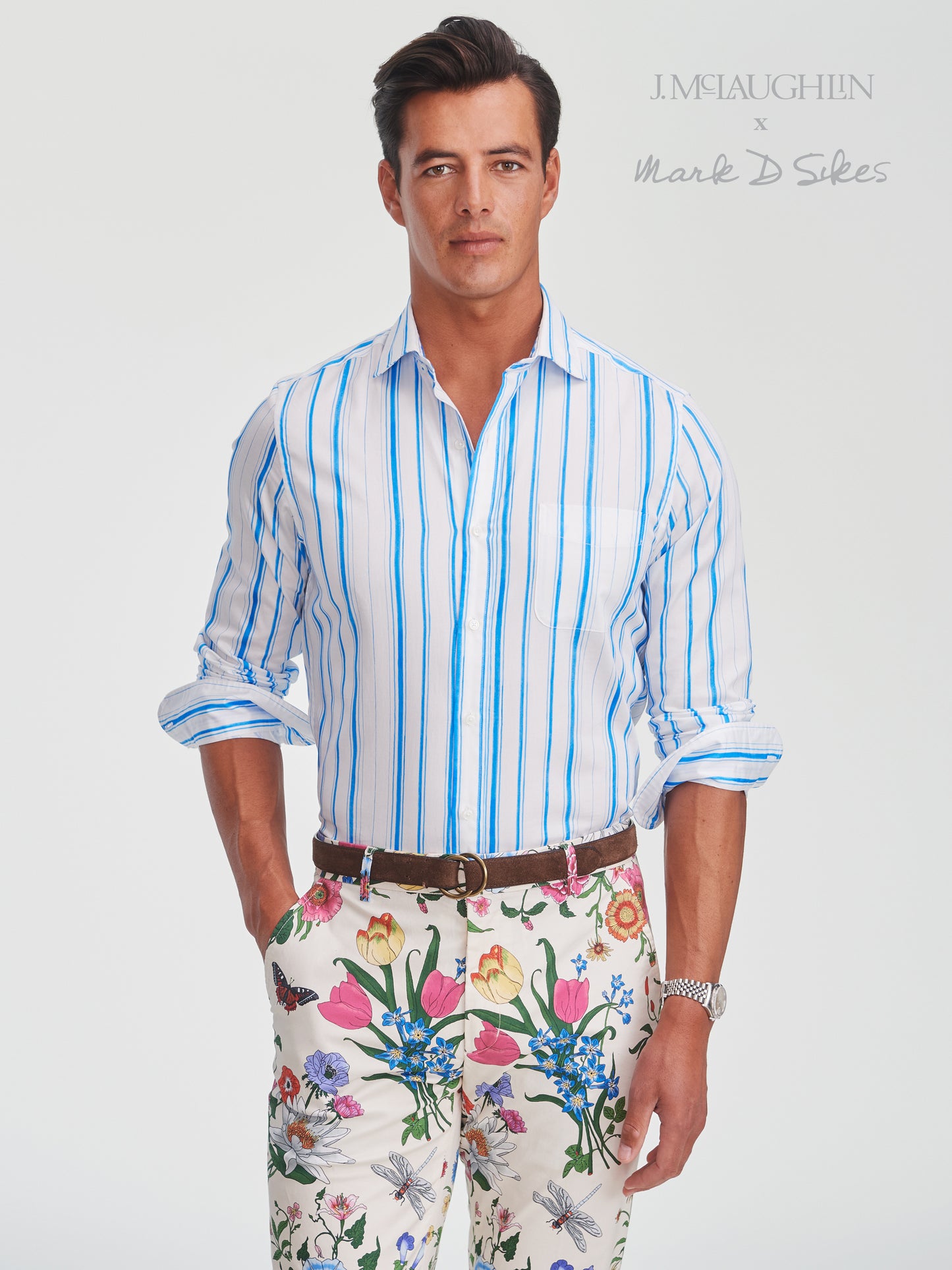 Man wearing a Gramercy Cotton Shirt in Coastal Waterline by J.McLaughlin, styled with floral patterned pants, showcasing effortlessly stylish, enduring designs and innovative fabrics.