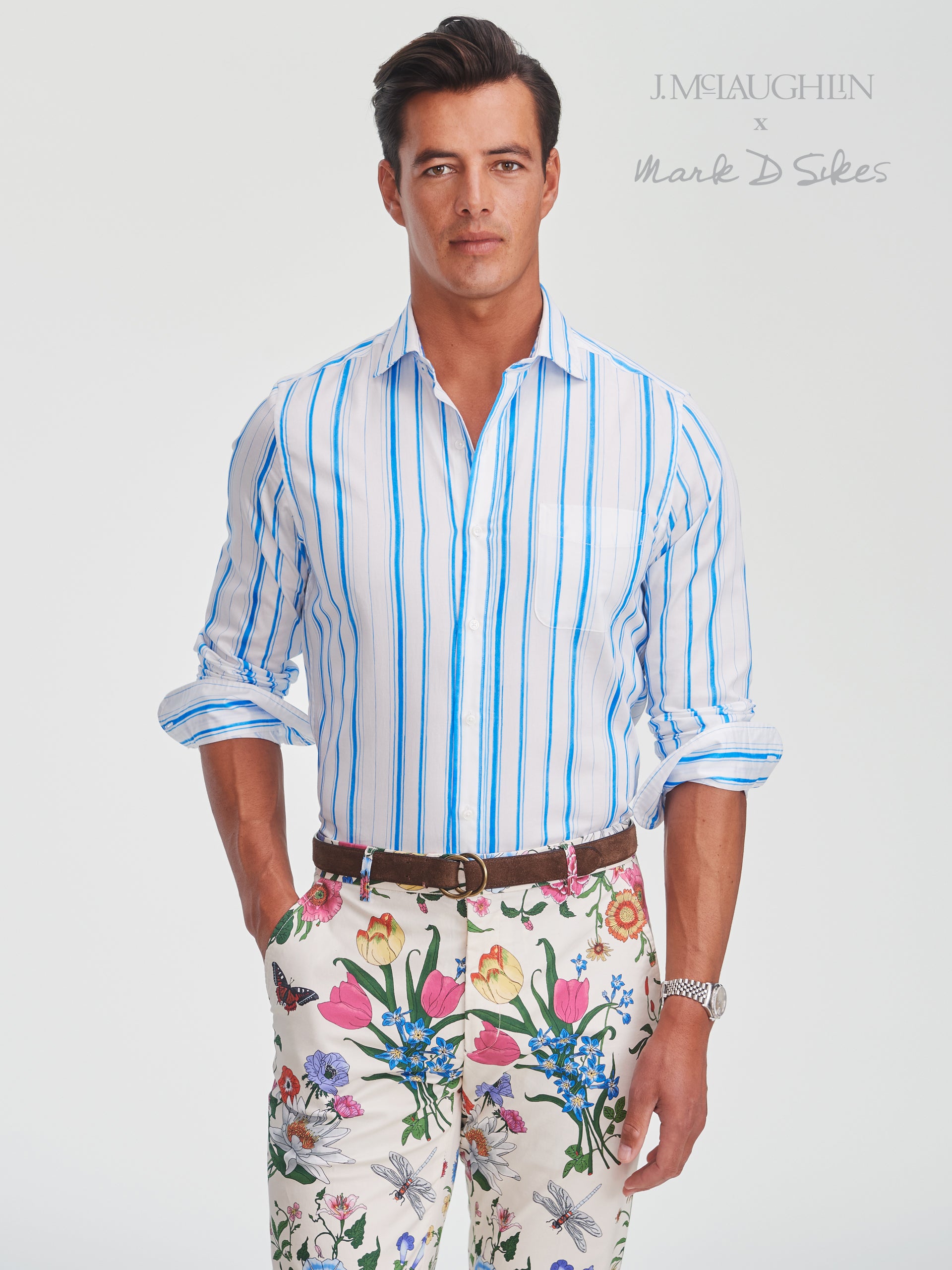 Man wearing a Gramercy Cotton Shirt in Coastal Waterline by J.McLaughlin, styled with floral patterned pants, showcasing effortlessly stylish, enduring designs and innovative fabrics.