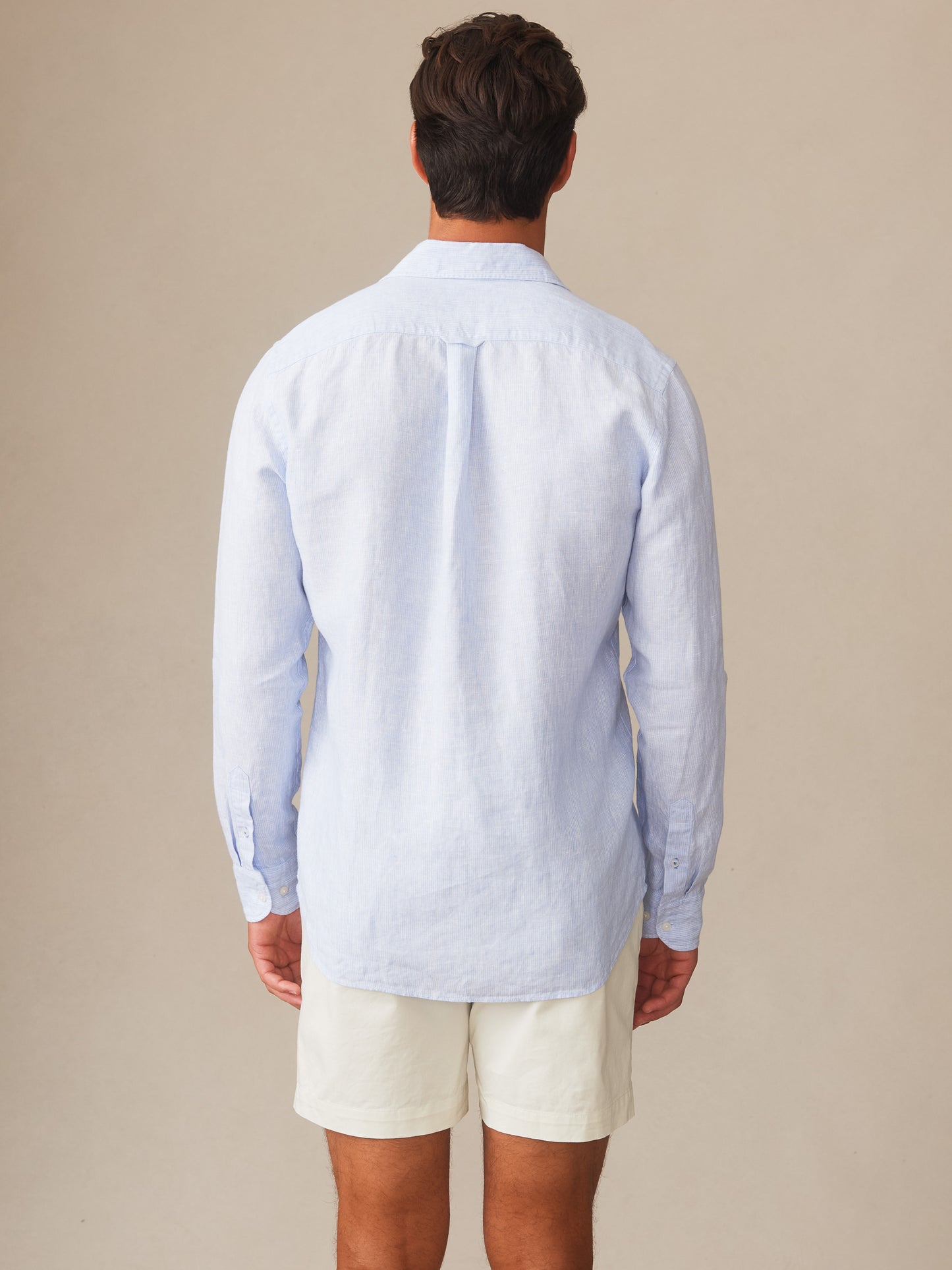 Man wearing a light blue Gramercy Linen Shirt in Hairline Stripe by J.McLaughlin, showcasing effortlessly stylish, enduring designs crafted from innovative fabrics in a timeless look.