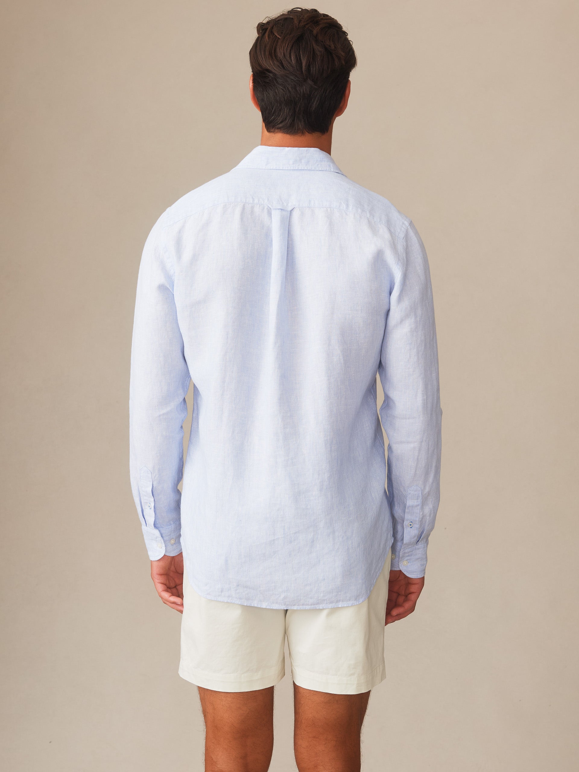 Man wearing a light blue Gramercy Linen Shirt in Hairline Stripe by J.McLaughlin, showcasing effortlessly stylish, enduring designs crafted from innovative fabrics in a timeless look.