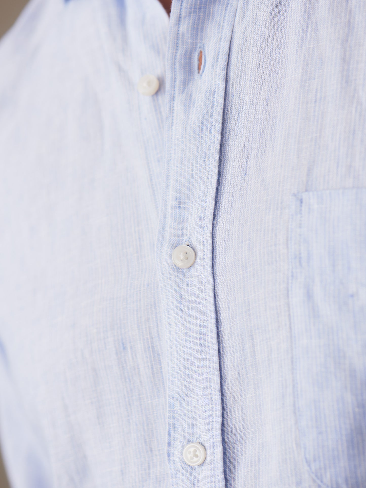 Close-up of the Gramercy Linen Shirt in Hairline Stripe by J.McLaughlin, showcasing its finely crafted blue and white striped linen fabric, reflecting effortlessly stylish, enduring designs and a legacy of timeless fashion at a destination for defining style. Life, Well-Lived.