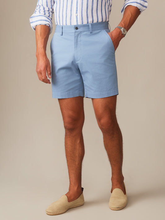 Man wearing light blue Chatham Shorts by J.McLaughlin paired with a striped shirt and beige slip-on shoes, showcasing effortlessly stylish, enduring designs for a life well-lived.