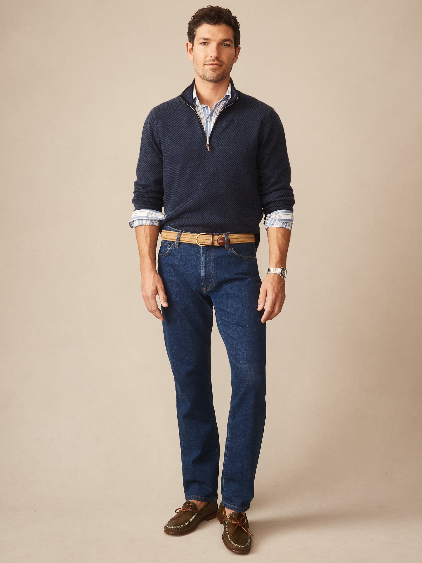 Man wearing J.McLaughlin Twain Cashmere 1/4 Zip in Jacquard navy sweater over a striped shirt, paired with blue jeans and casual brown shoes, showcasing effortlessly stylish, enduring designs.