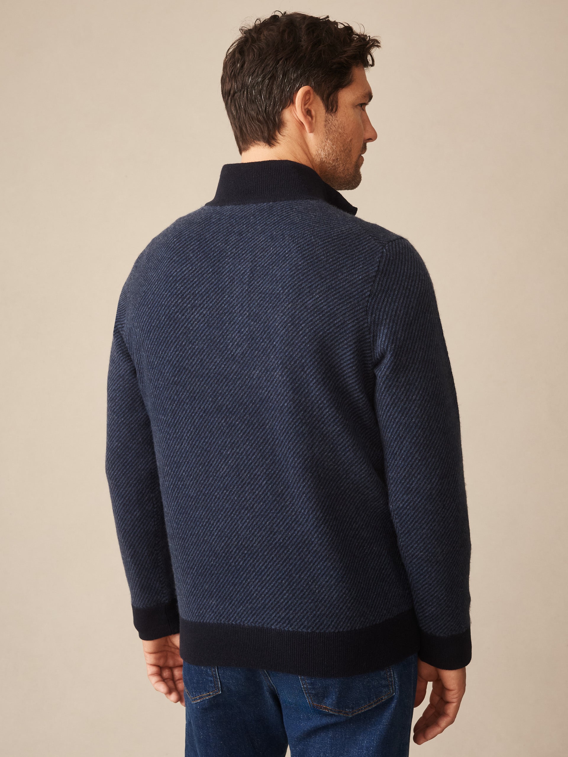 Man wearing a navy textured sweater with contrasting collar and cuffs, showcasing the Twain Cashmere 1/4 Zip in Jacquard by J.McLaughlin, effortlessly stylish with enduring designs and innovative fabrics.