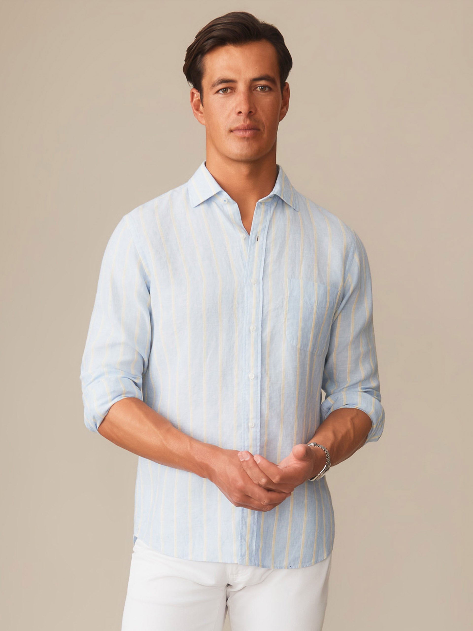 A man wearing a Gramercy Linen Shirt in Dobby Stripe by J.McLaughlin, featuring effortlessly stylish design and innovative fabrics for enduring appeal in timeless fashion.