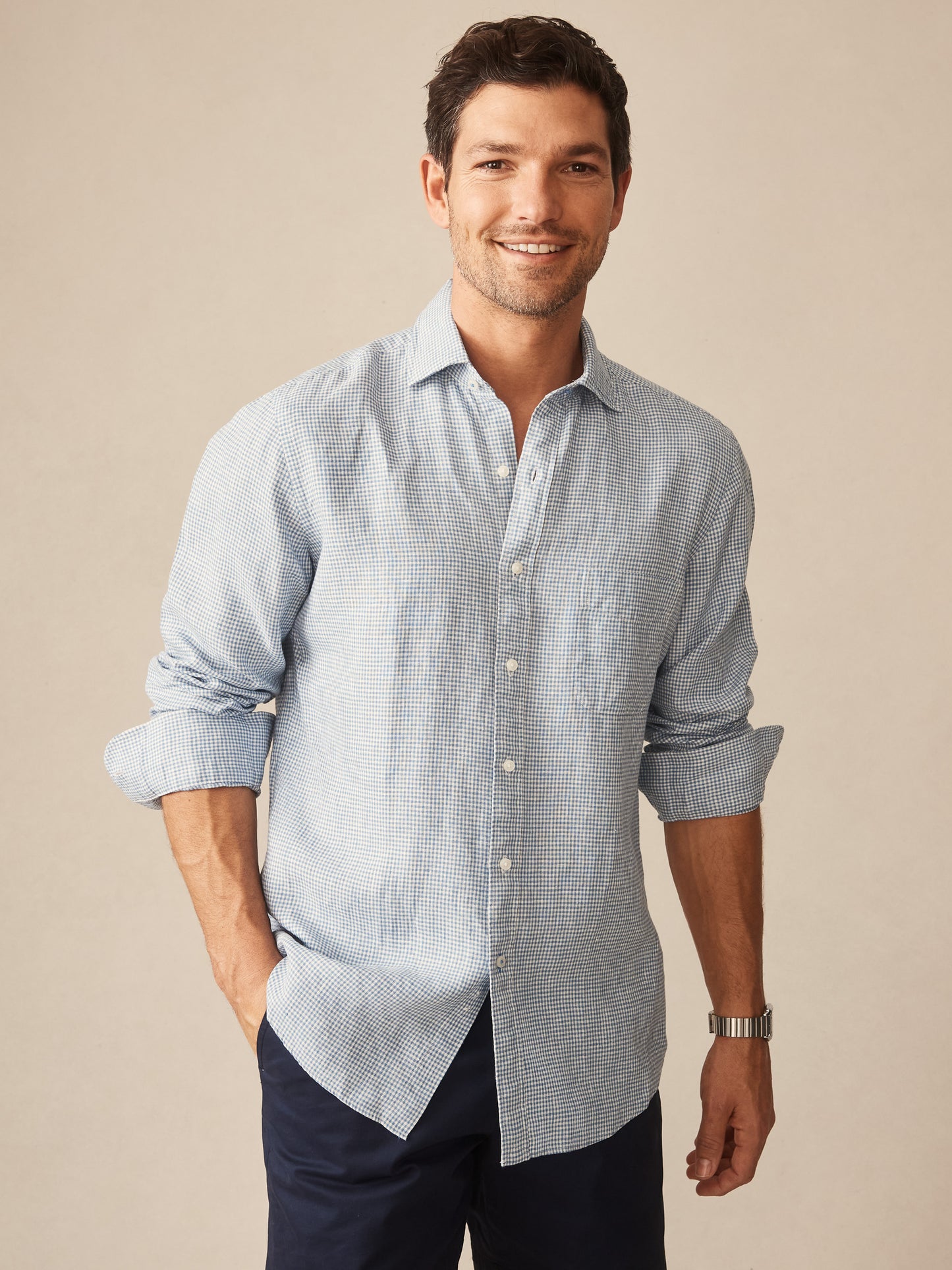 Man wearing a light blue and white Gramercy Linen Shirt in Micro Gingham by J.McLaughlin, combining effortlessly stylish design and innovative fabrics for enduring designs.