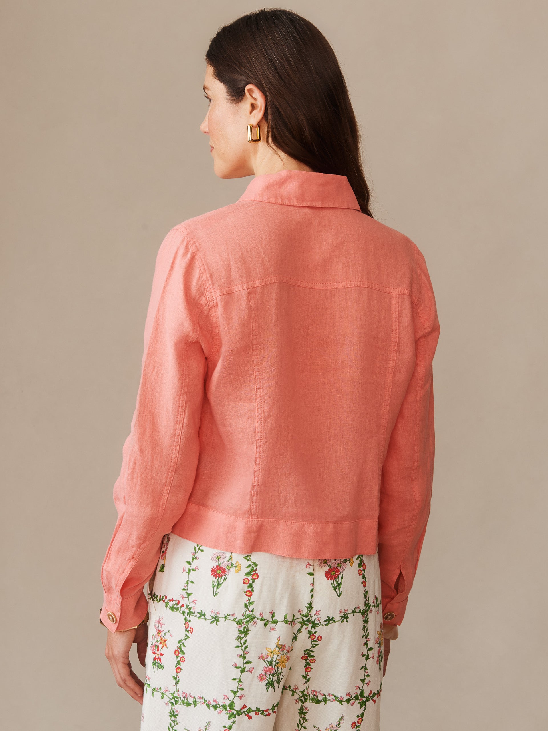 A back view of a woman wearing the Halo Linen Jacket in a soft coral shade by J.McLaughlin, showcasing effortlessly stylish design and enduring fabrics for a legacy of timeless fashion.