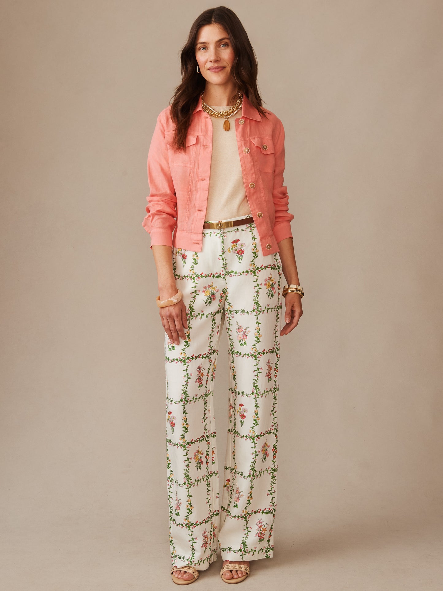 Woman wearing a coral Halo Linen Jacket by J.McLaughlin over a light top paired with white floral patterned wide-leg pants, showcasing effortlessly stylish, enduring designs with innovative fabrics for a legacy of timeless fashion.