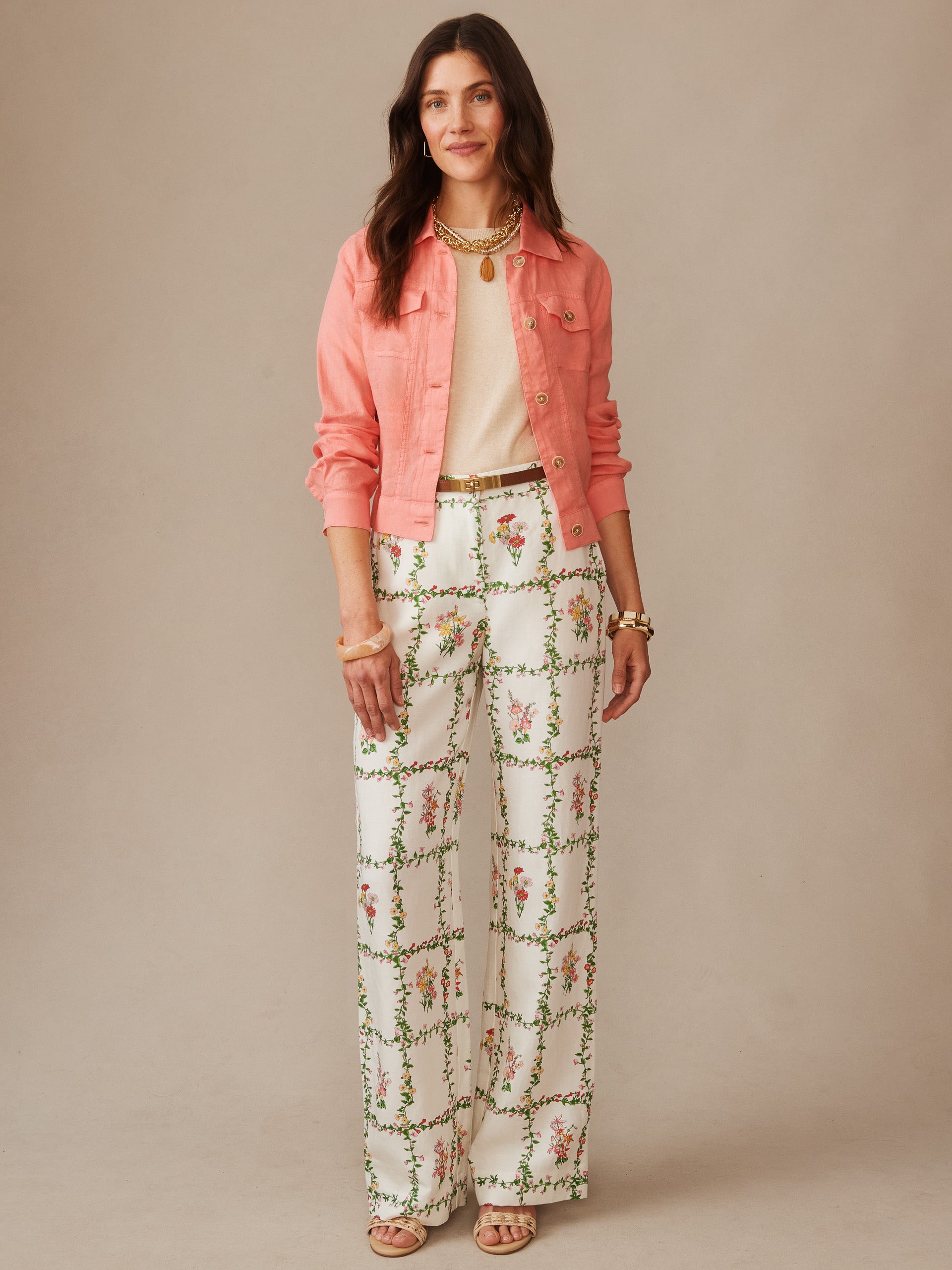 Woman wearing a coral Halo Linen Jacket by J.McLaughlin over a light top paired with white floral patterned wide-leg pants, showcasing effortlessly stylish, enduring designs with innovative fabrics for a legacy of timeless fashion.