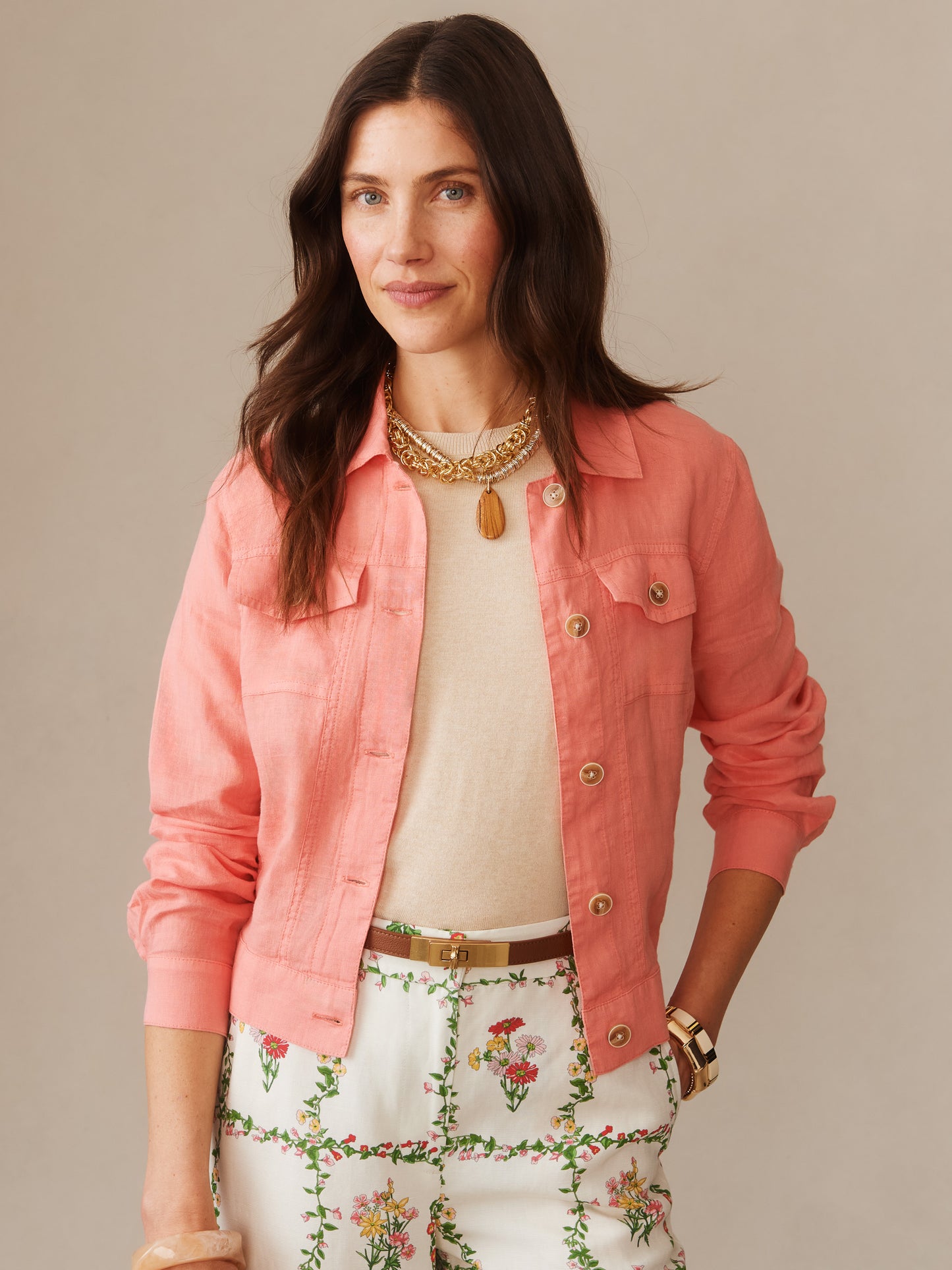 A woman wearing the effortlessly stylish Halo Linen Jacket by J.McLaughlin in a coral shade, paired with floral patterned pants, showcasing enduring designs and innovative fabrics from a destination for defining style. Life, Well-Lived.