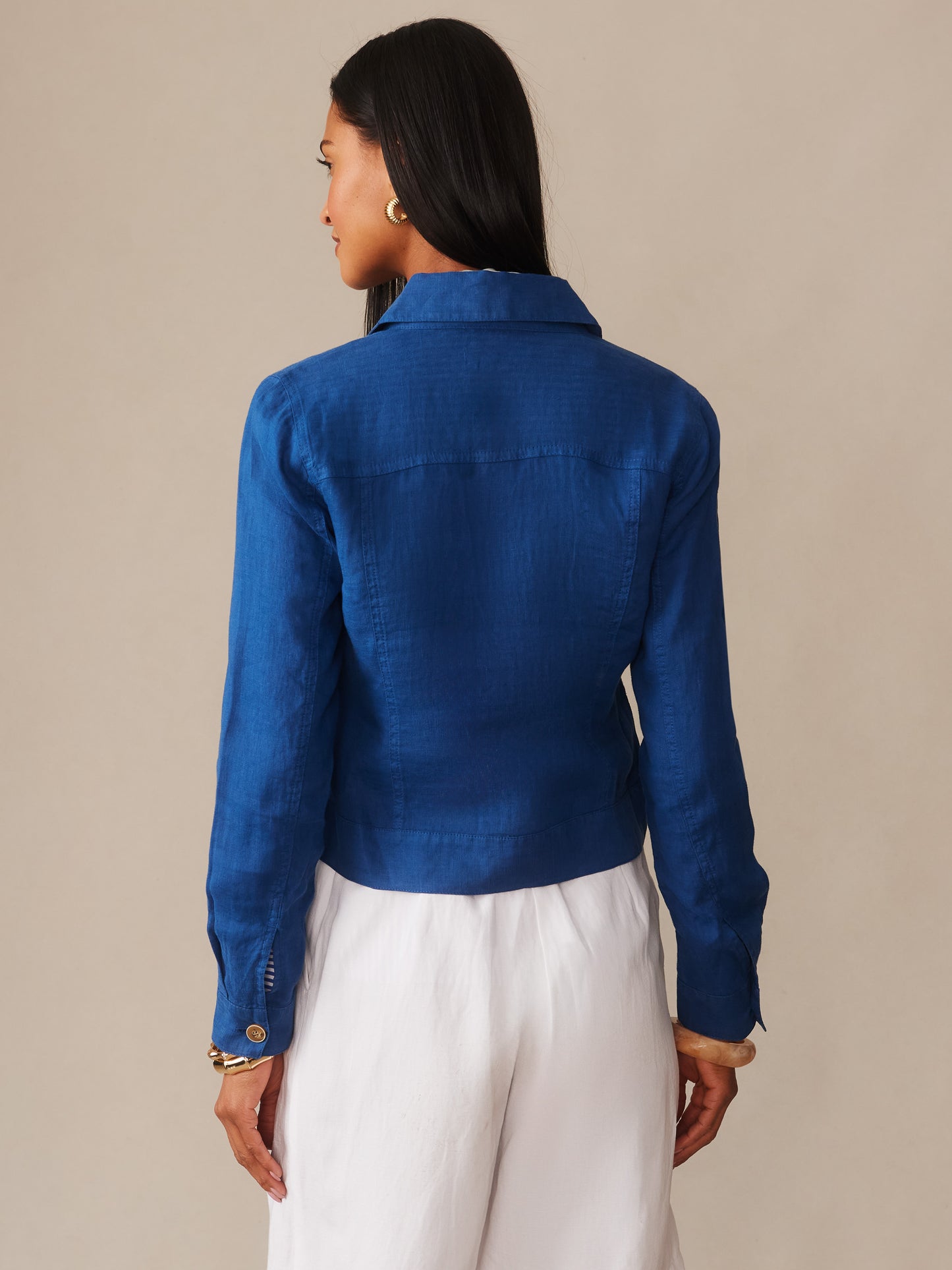 Woman seen from behind wearing a navy blue Halo Linen Jacket by J.McLaughlin paired with white pants, showcasing effortlessly stylish design and innovative fabrics for a life well-lived.