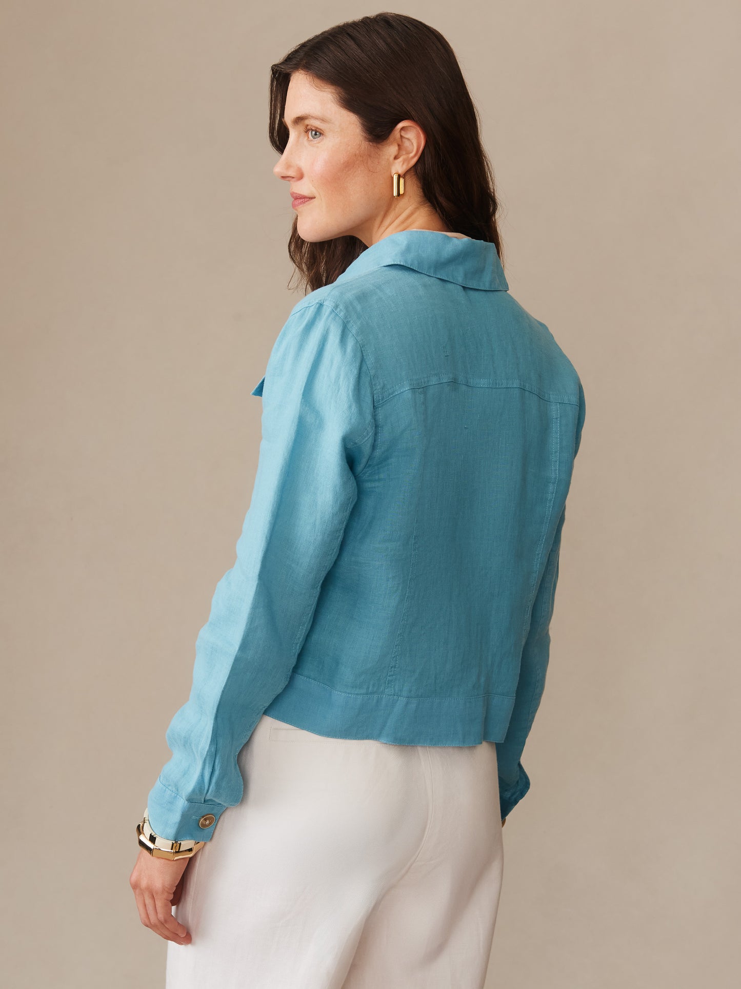 A woman wearing a teal Halo Linen Jacket by J.McLaughlin, showcasing effortlessly stylish layering with enduring designs crafted from innovative fabrics for a legacy of timeless fashion.