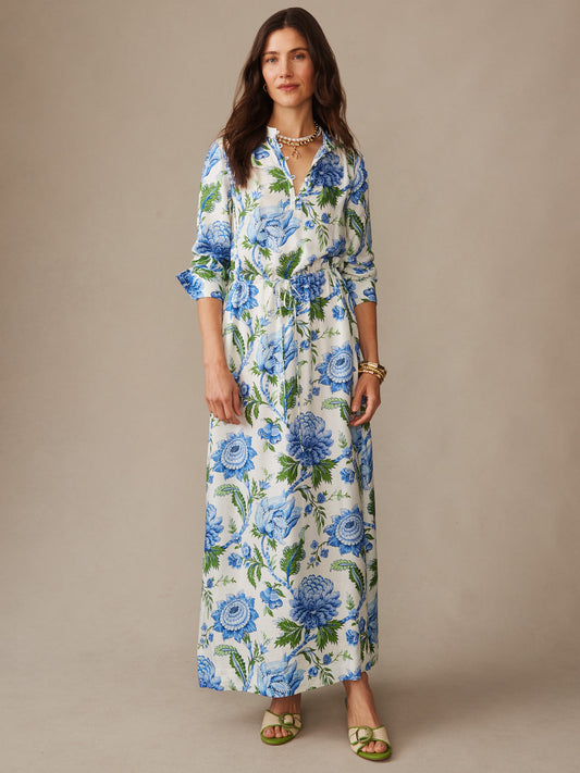 Woman wearing the Hannah Silk Blend Dress in Cerulean Garden by J.McLaughlin, featuring a blue and green floral print on an off-white background, styled with bracelets and sandals, showcasing effortlessly stylish, enduring designs with innovative fabrics from a destination for defining style. Life, Well-Lived.